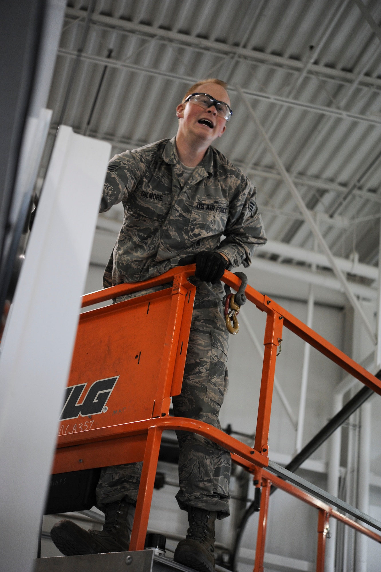 Senior Airman Brandon Gilmore, 91st Missile Operations Squadron mechanical and pneudraulics section technician, calls out instructions for his teammates from a bucket lift during maintenance on a crane on Minot Air Force Base, N.D. Oct. 30, 2014. Gilmore worked with a team of other MAPS Airmen to replace the cranes main cable. (U.S. Air Force photo/Senior Airman Stephanie Morris)