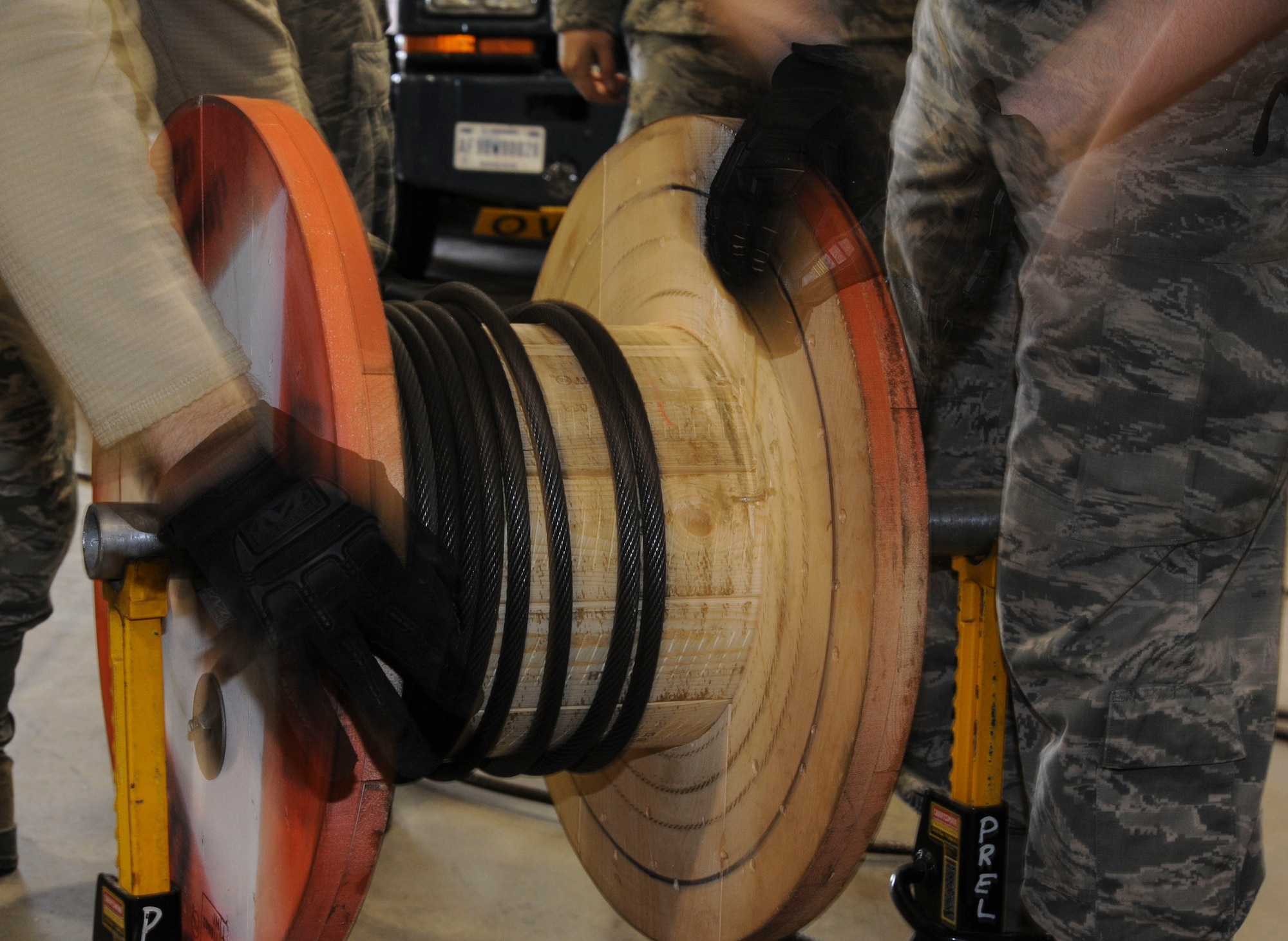 Members of the 91st Missile Operations Squadron mechanical and pneudraulics section work together to wind a cable from a crane onto a spool on Minot Air Force Base, N.D. Oct. 30, 2014. The team utilized constant communication during the process to ensure they were utilizing a two-person concept and nothing was overlooked. (U.S. Air Force photo/Senior Airman Stephanie Morris)