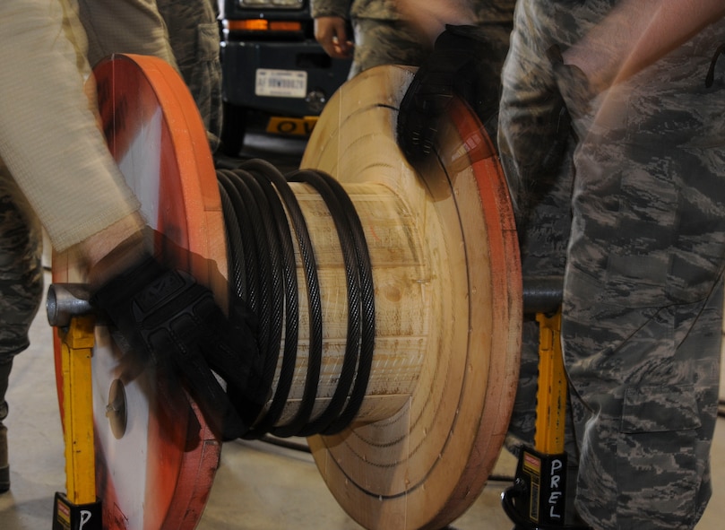 Members of the 91st Missile Operations Squadron mechanical and pneudraulics section work together to wind a cable from a crane onto a spool on Minot Air Force Base, N.D. Oct. 30, 2014. The team utilized constant communication during the process to ensure they were utilizing a two-person concept and nothing was overlooked. (U.S. Air Force photo/Senior Airman Stephanie Morris)