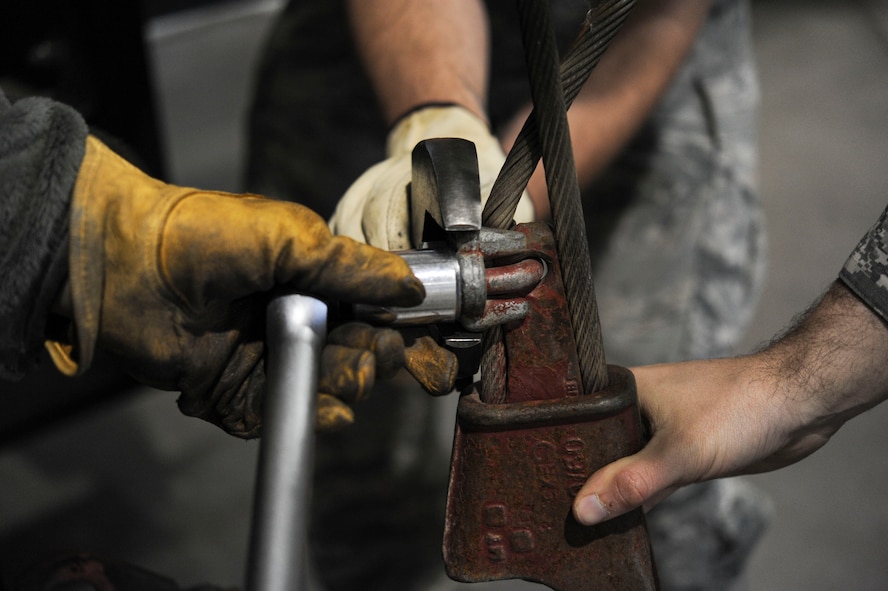 A group of 91st Missile Operations Squadron mechanical and pneudraulics section team members work together to remove a cable from a crane on Minot Air Force Base, N.D. Oct. 30, 2014. MAPS’s mission is to provide maintenance and upkeep of missile wing support equipment such as cranes, payload transporters and floor actuators in the alert facilities. (U.S. Air Force photo/Senior Airman Stephanie Morris)
