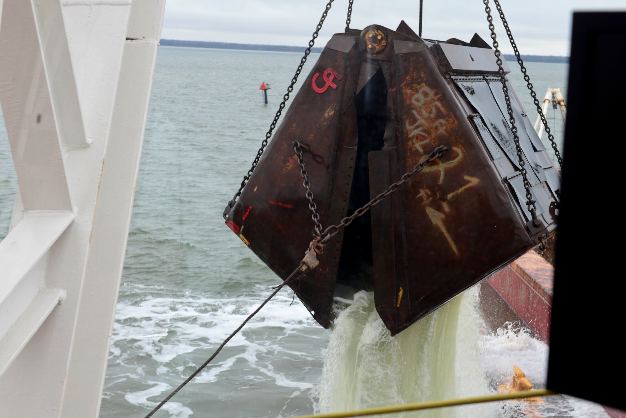 A spud-barge mounted crane is lifted out of the waters of 3rd Port at Fort Eustis, Va., Dec. 9, 2014. The crane is used to collect materials that have accumulated under water from various sources. (U.S. Air Force photo by Senior Airman Kimberly Nagle/Released)