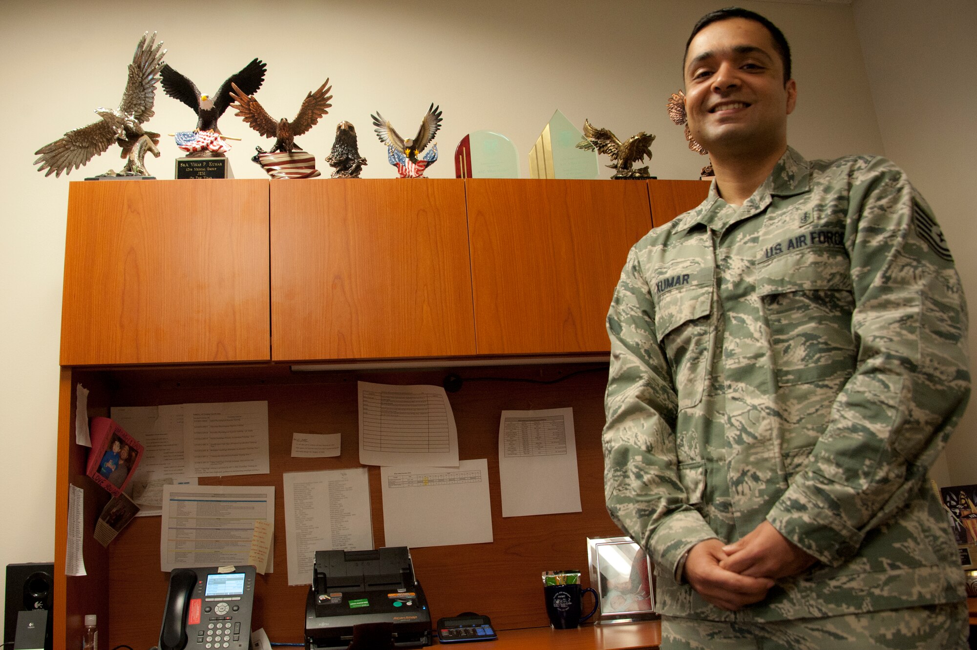 Tech. Sgt. Vikas Kumar, the 92nd Aerospace Medicine Squadron aerospace and physiology flight NCO in charge, poses in front of his work desk Dec. 4, 2014, at Fairchild Air Force Base, Wash. Kumar was 1 of 10 candidates to be selected for commission through the Biomedical Science Corp Direct Accession Program. (U.S. Air Force photo/Airman 1st Class Nicolo J. Daniello)