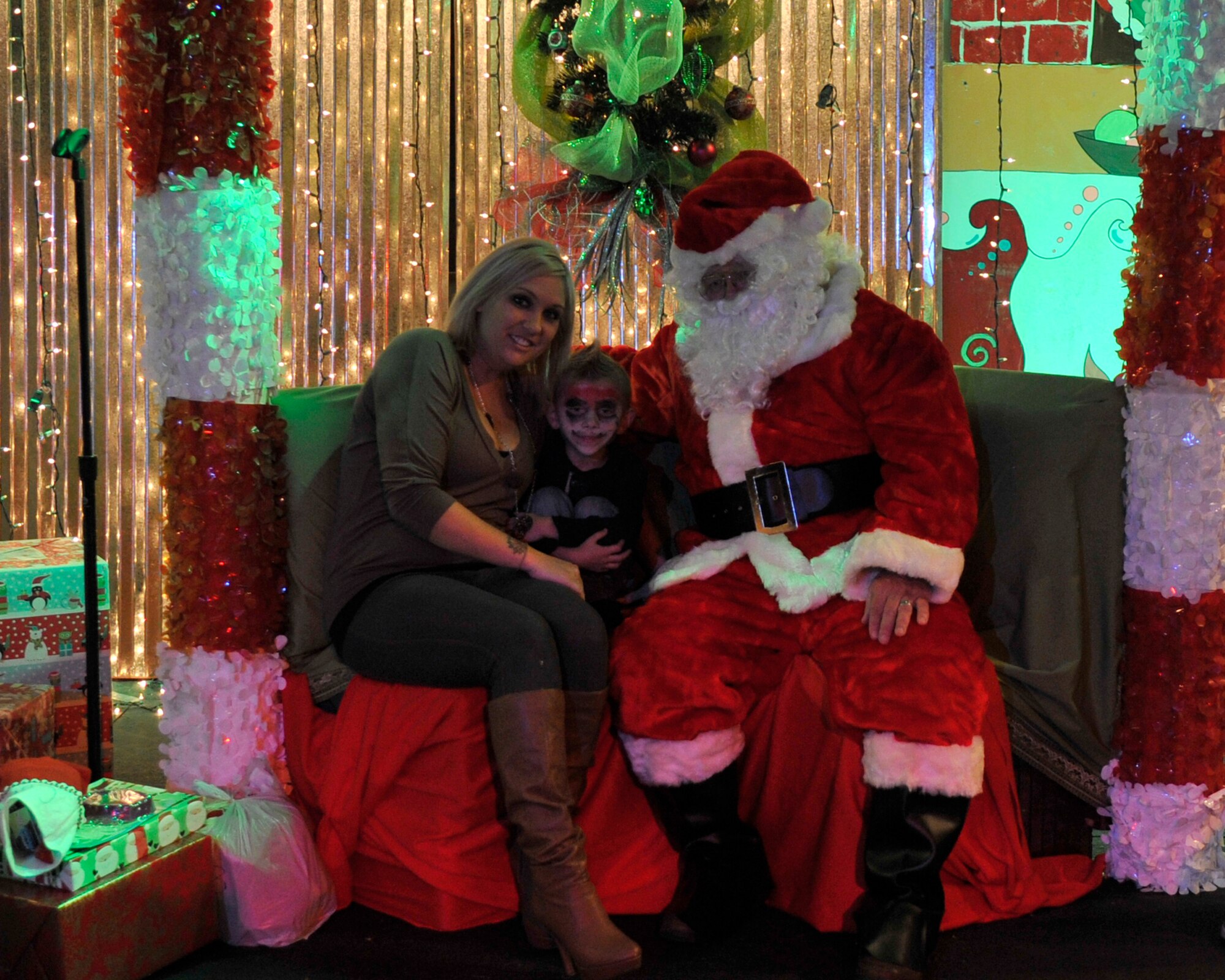 Colin Harrison, child of Staff Sgt. Richard Harrison, 95th Aircraft Maintenance Unit avionics specialist, and his mother Jennifer Harrison pose for a photo with Santa Claus Dec. 5 at the Hearts Apart Who-liday Party. Each child received a personal gift and photo with Santa Claus. (U.S. Air Force photo by Airman 1st Class Ty-Rico Lea)