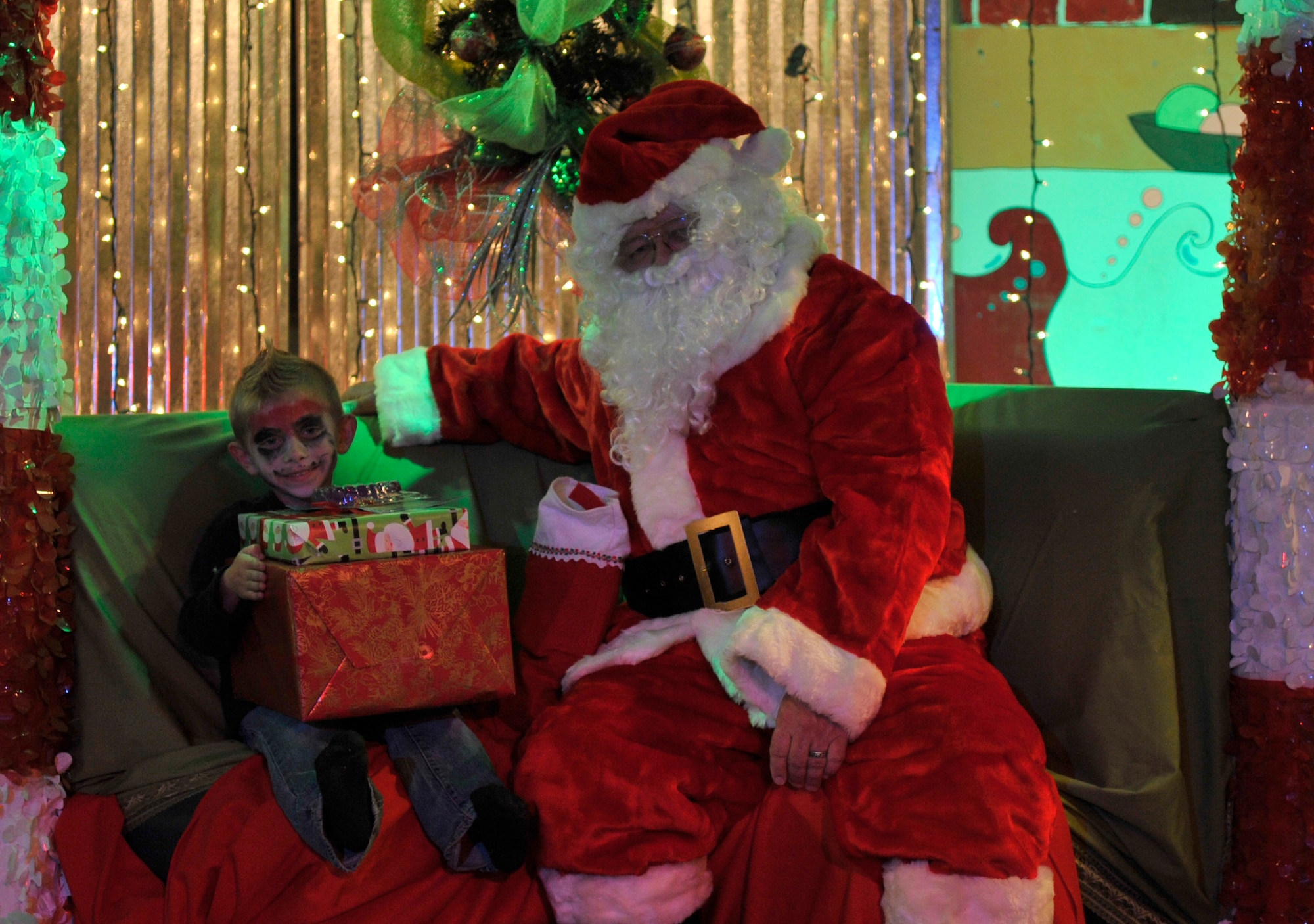 Colin Harrison, 5, child of Staff Sgt. Richard Harrison, 95th Aircraft Maintenance Unit avionics specialist, pose for a photo with Santa Claus at the Hearts Apart Who-liday Party Dec. 5. Each child received a personal gift and photo with Santa Claus. (U.S. Air Force photo by Airman 1st Class Ty-Rico Lea)