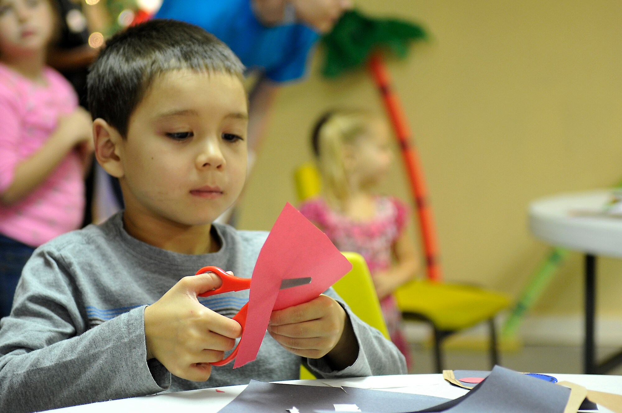 Corbyn Stevens, child of Master Sgt. Philip Stevens, 325th Maintenance Squadron munitions swing-shift superintendent, makes paper holiday ornaments Dec. 5 at the Hearts Apart Who-liday Party. The Hearts Apart event is done specifically for families with loved ones that are deployed or on remote assignments. (U.S. Air Force photo by Airman 1st Class Ty-Rico Lea)