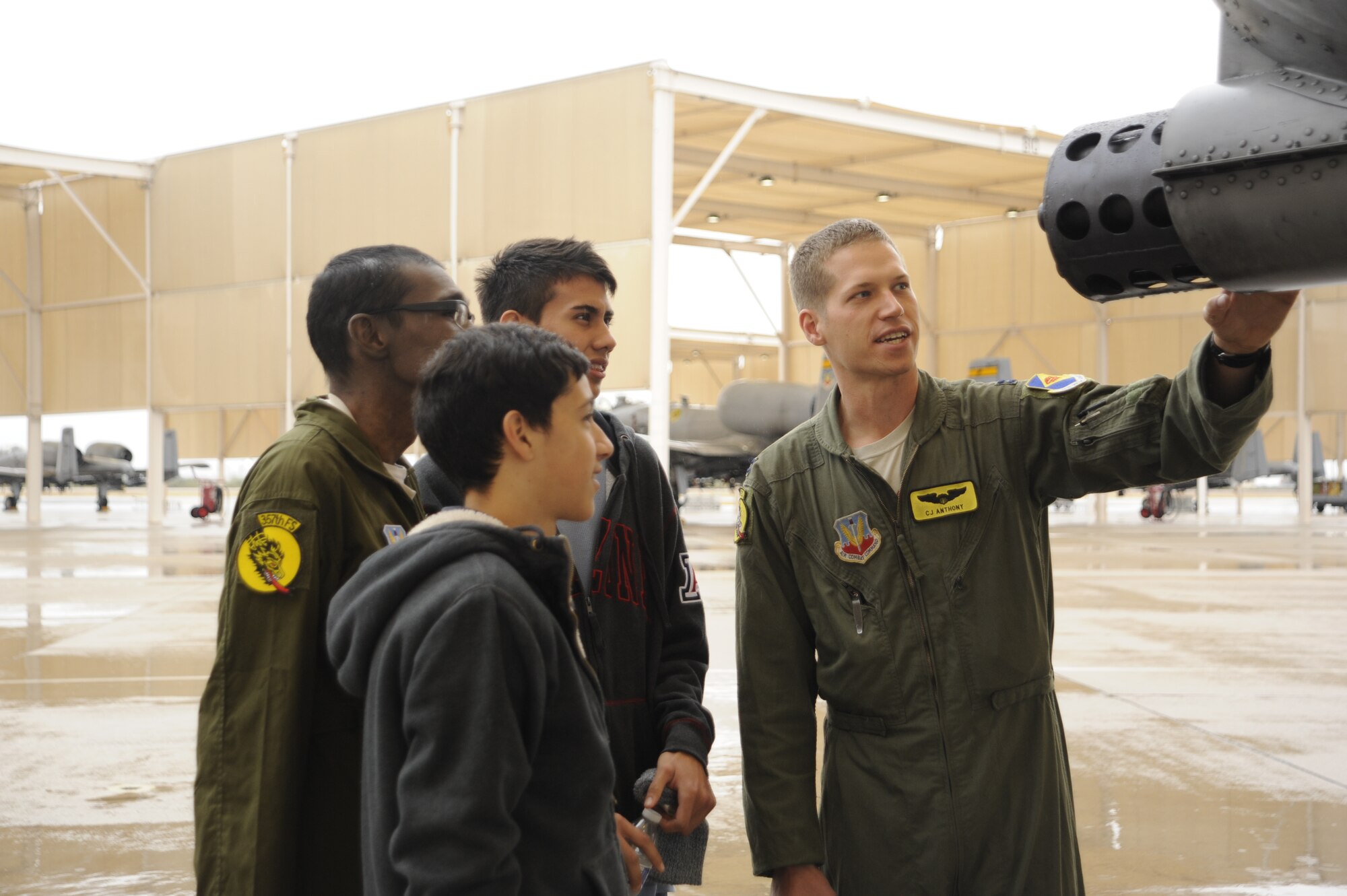 U.S. Air Force Capt. Christopher Anthony, 357th Fight Squadron Pilot for a Day host pilot, teaches Sergio Quiroz, an honorary pilot, and his cousins about the A-10C Thunderbolt II during a tour for the Pilot for a Day program at Davis-Monthan Air Force Base, Ariz., Dec. 4, 2014. During the visit, Quiroz was inducted into the 357th FS where him and his cousins tried on pilot flight equipment, visited the A-10 and parachute simulators and toured the air traffic control tower. (U.S. Air Force photo by Airman 1st Class Betty R. Chevalier)
