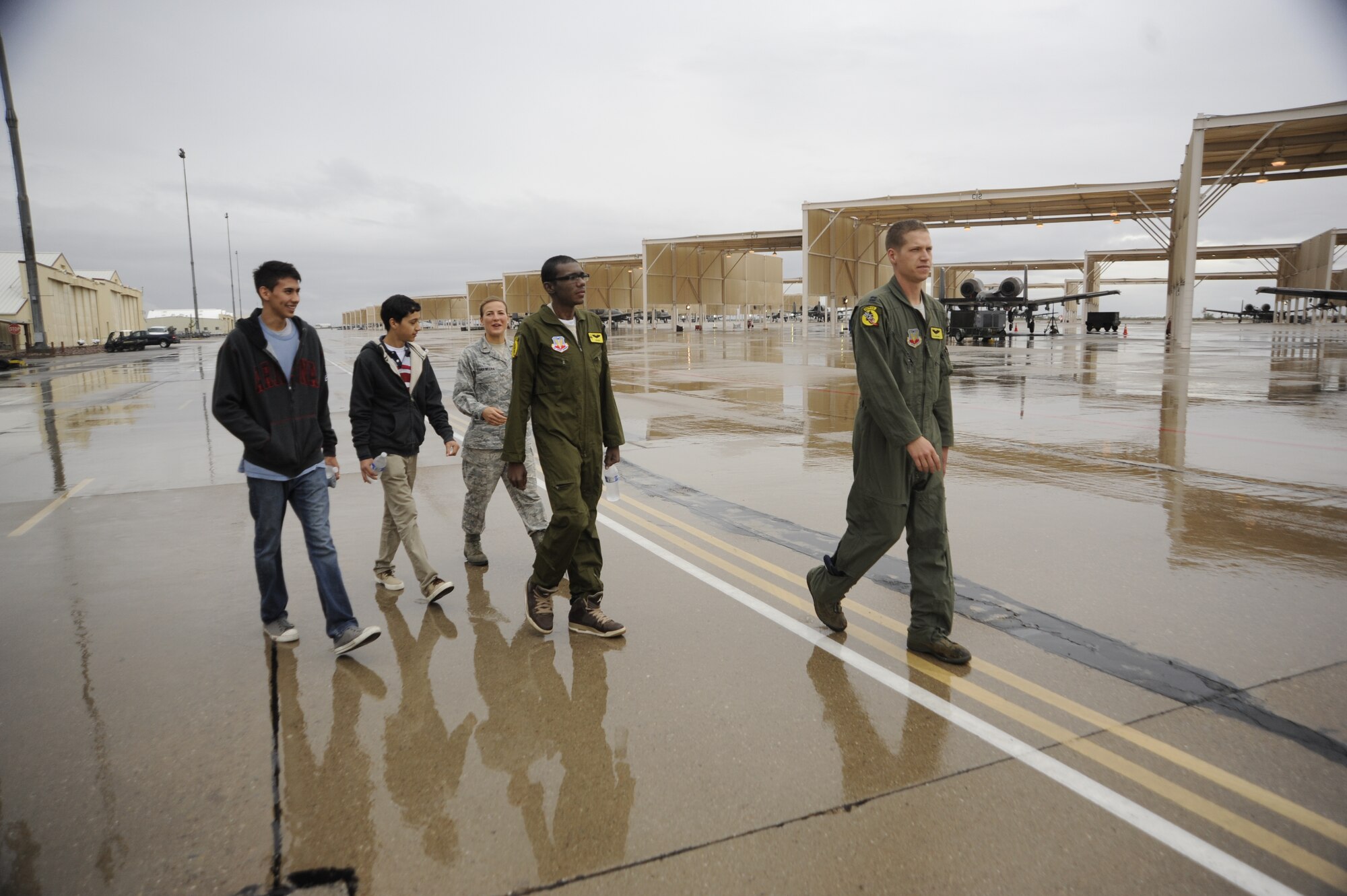 U.S. Air Force Capt. Christopher Anthony, 357th Fight Squadron Pilot for a Day host pilot, leads Sergio Quiroz, an honorary pilot, and his cousins to an A-10C Thunderbolt II static during the Pilot for Day program at Davis-Monthan Air Force Base, Ariz., Dec. 4, 2014. The Pilot for a Day program invites local young individuals battling severe illnesses and conditions to be a guest of the 355th Fighter Wing and one of D-M's flying squadrons for an entire day. (U.S. Air Force photo by Airman 1st Class Betty R. Chevalier)