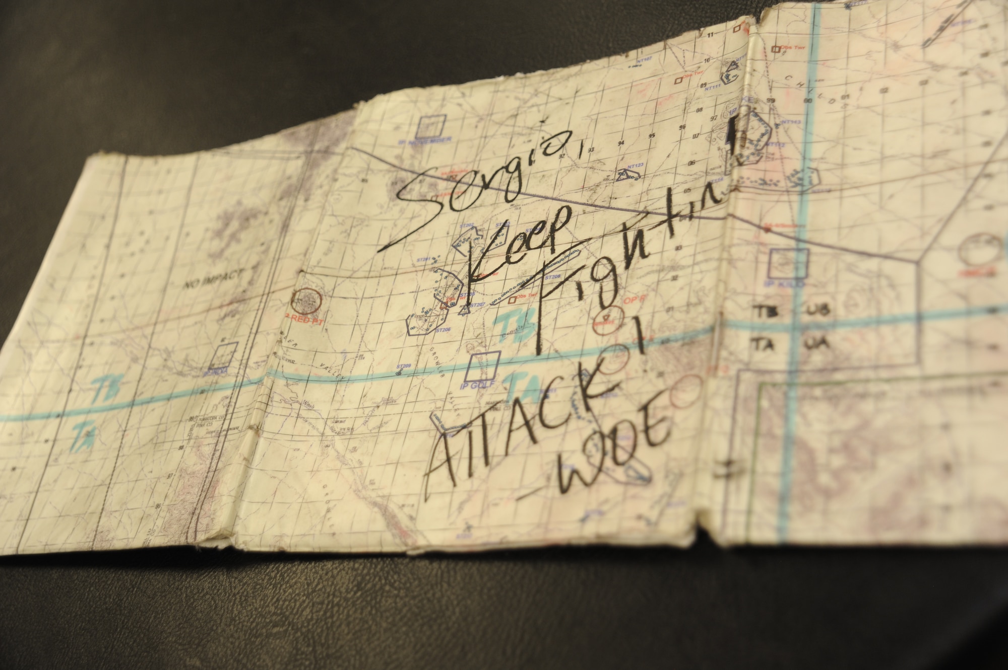 A map signed by a member of the 357th Fighter Squadron sits on a table before being presented to Sergio Quiroz, an honorary pilot who visited the squadron for the Pilot for a Day program at Davis-Monthan Air Force Base, Ariz., Dec. 4, 2014. During the visit, Quiroz was inducted into the 357th FS where him and his cousins tried on pilot flight equipment, visited the A-10 and parachute simulators and toured the air traffic control tower. (U.S. Air Force photo by Airman 1st Class Betty R. Chevalier)