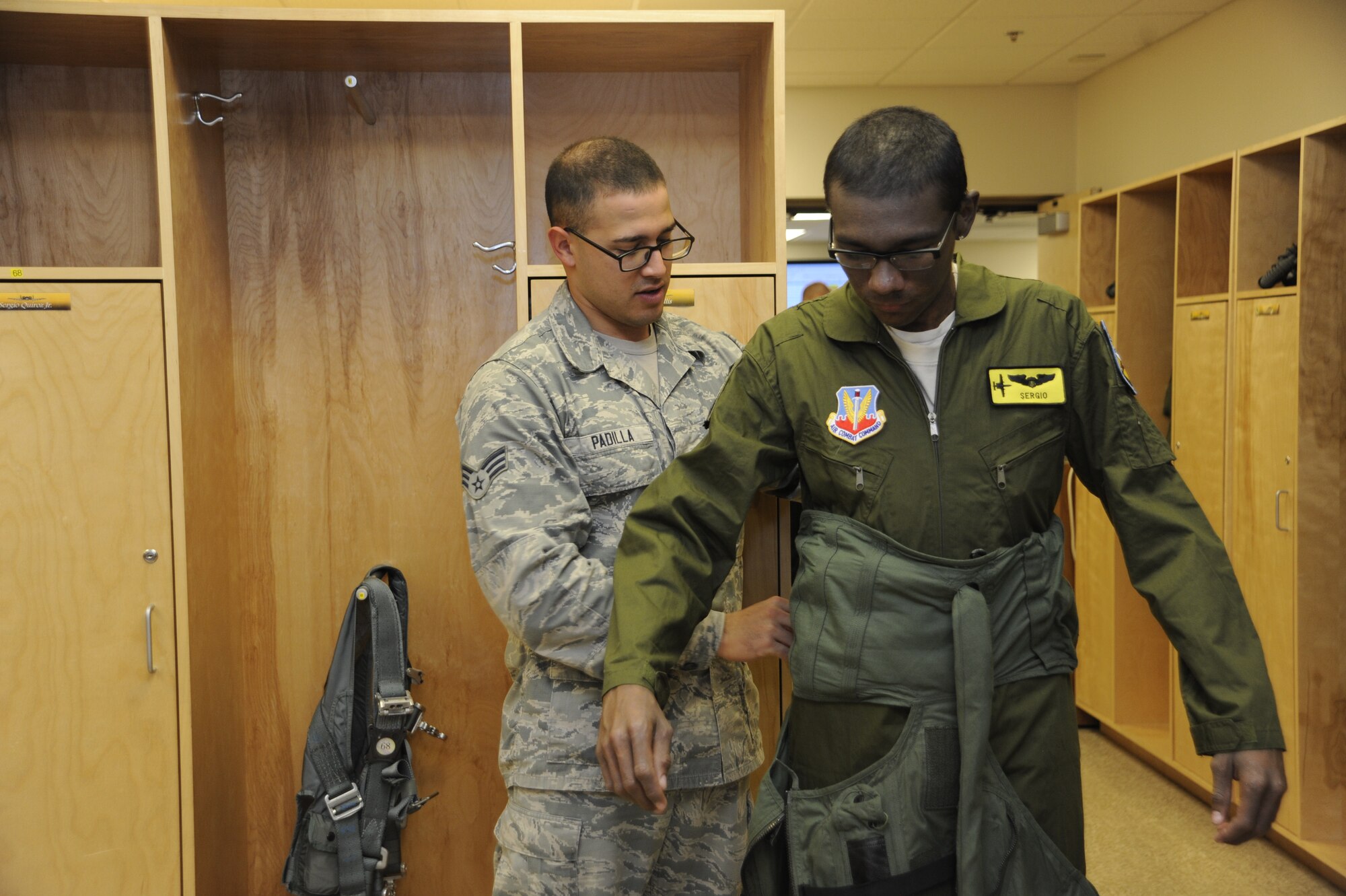U.S. Air Force Senior Airman Jose Padilla, 355th Operations Support Squadron aircrew flight equipment technician, helps Sergio Quiroz, an honorary pilot, put on a G-suit during part of Quiroz’ base tour for the Pilot for a Day program at Davis-Monthan Air-Force Base, Ariz., Dec. 4, 2014. The Pilot for a Day program invites local young individuals battling severe illnesses and conditions to be a guest of the 355th Fighter Wing and one of D-M's flying squadrons for an entire day. (U.S. Air Force photo by Airman 1st Class Betty R. Chevalier)