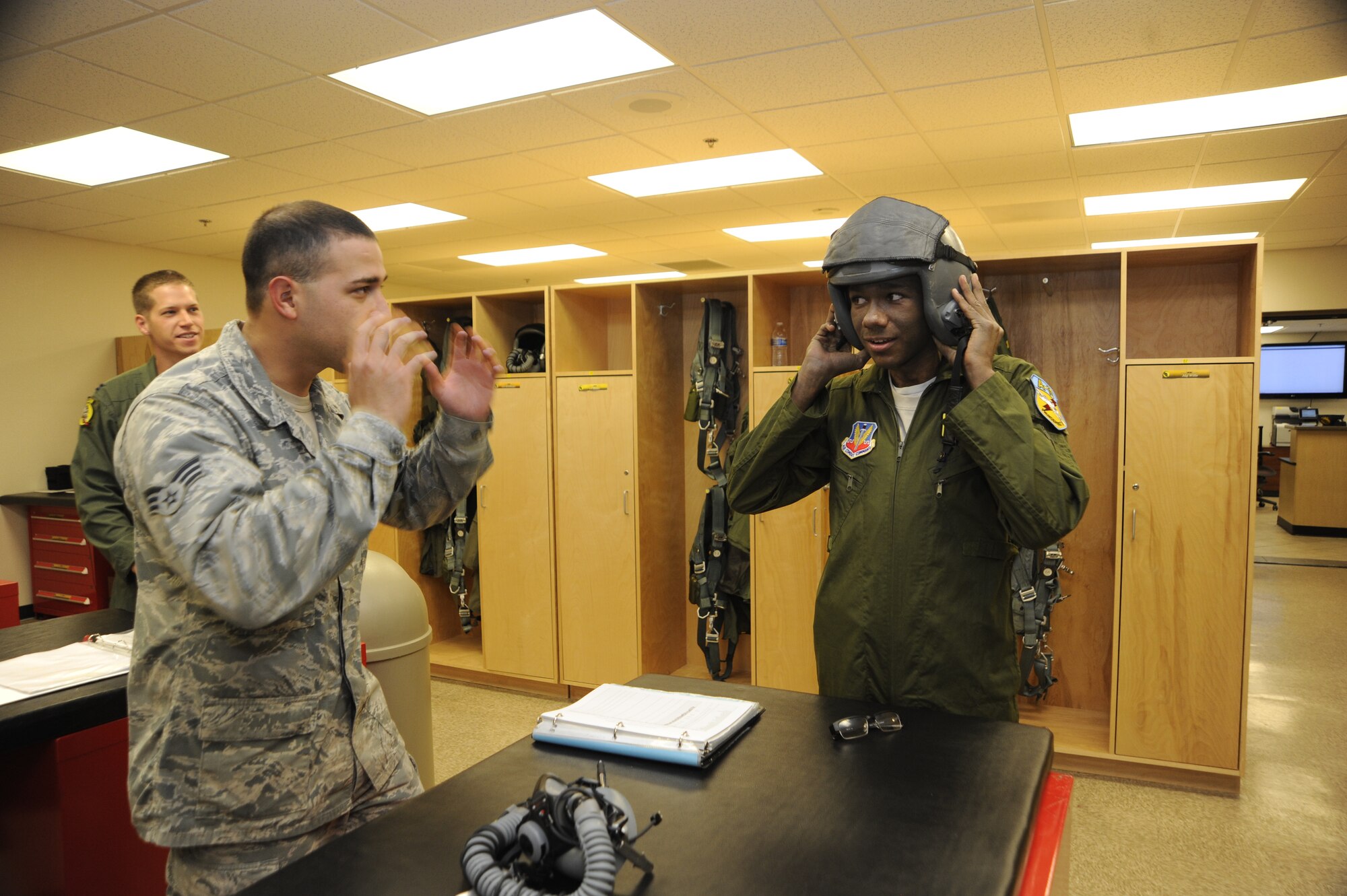 U.S. Air Force Senior Airman Jose Padilla, 355th Operations Support Squadron aircrew flight equipment technician, explains how to don a pilot helmet to Sergio Quiroz, an honorary pilot, at Davis-Monthan Air Force Base, Ariz., Dec. 4, 2014. The Pilot for a Day program invites local young individuals battling severe illnesses and conditions to be a guest of the 355th Fighter Wing and one of D-M's flying squadrons for an entire day. (U.S. Air Force photo by Airman 1st Class Betty R. Chevalier)