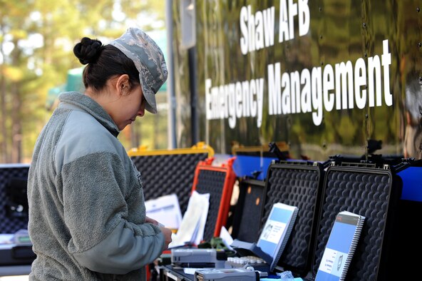 U.S. Air Force Airman 1st Class Cynthia Romero, 20th Civil Engineer Squadron emergency management apprentice, examines her gear during an integrated base emergency response capability training at Shaw Air Force Base, S.C., Dec. 9, 2014. The 20th CES emergency management flight and the 20th Aerospace Medicine Squadron bioenviromental flight were tested on their abilities to react and work together in the event of a chemical attack were to happen on base. (U.S. Air Force photo by Airman 1st Class Michael Cossaboom/Released)