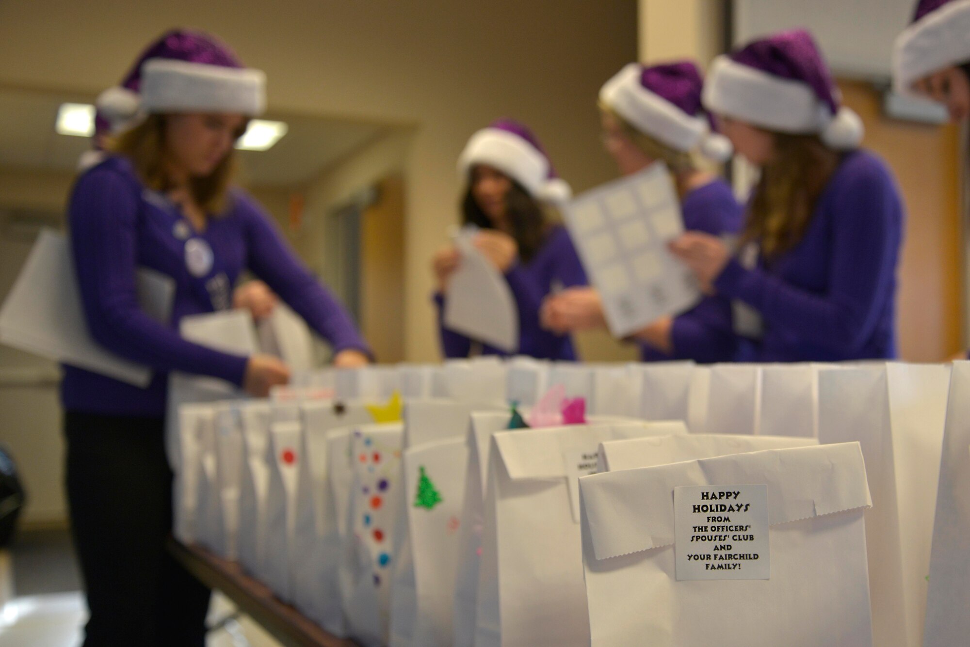 Spokane Lilac Festival’s FAB 14 fill bags of cookies Dec. 8, 2014, at Fairchild Air Force Base, Wash. The FAB 14 ladies volunteered to assist the Officer’s Spouses Club in their annual Operation Cookie Drop where they distribute bags of cookies to Airmen in the dormitories. (U.S. Air Force photo/ Senior Airman Janelle Patiño) 