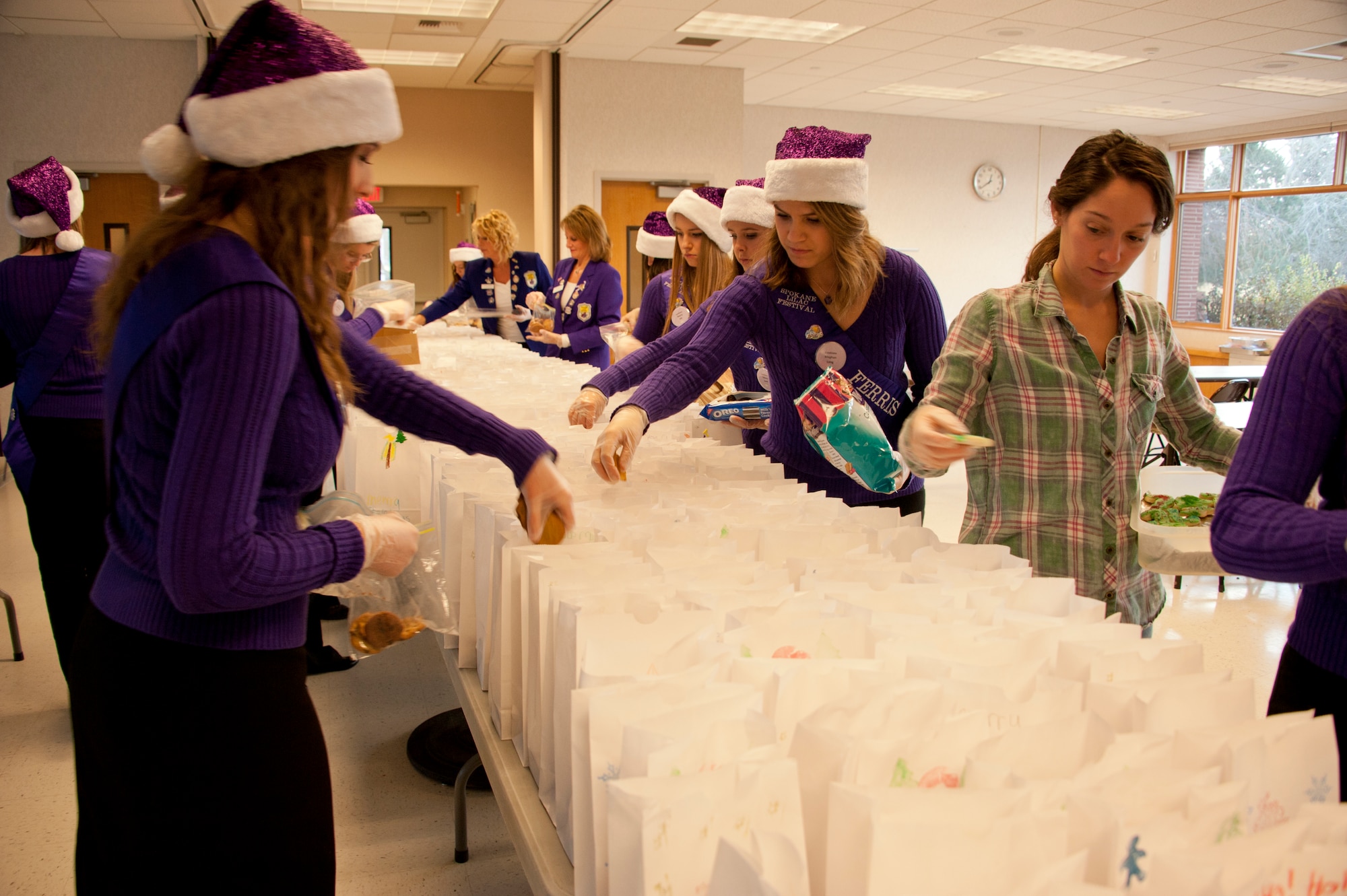 Spokane Lilac Festival’s FAB 14 place cookies into holiday bags Dec. 8, 2014, at Fairchild Air Force Base, Wash. The FAB 14 assisted the Officer’s Spouses Club with bagging cookies for their annual Operation Cookie Drop where they distributed bags of cookies to the Airmen living in the dormitories here. (U.S. Air Force photo/Airman 1st Class Nicolo J. Daniello)