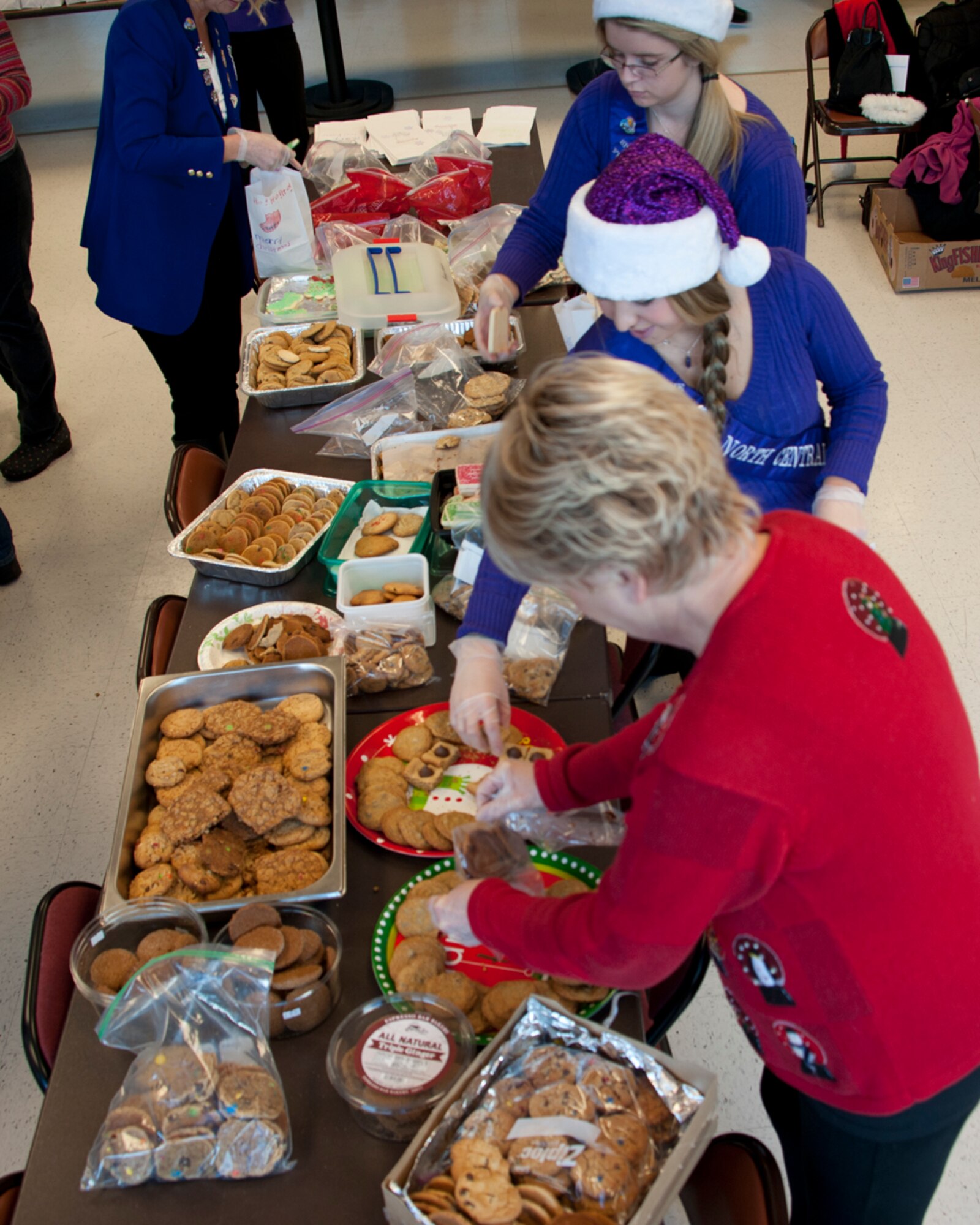 Spokane Lilac Festival’s FAB 14 choose cookies to place into holiday bags Dec. 8, 2014, at Fairchild Air Force Base, Wash. The FAB 14 volunteered to assist the Officer’s Spouses Club in bagging and distributing cookies to the Airmen who live in the dormitories on base. (U.S. Air Force photo/Airman 1st Class Nicolo J. Daniello)
