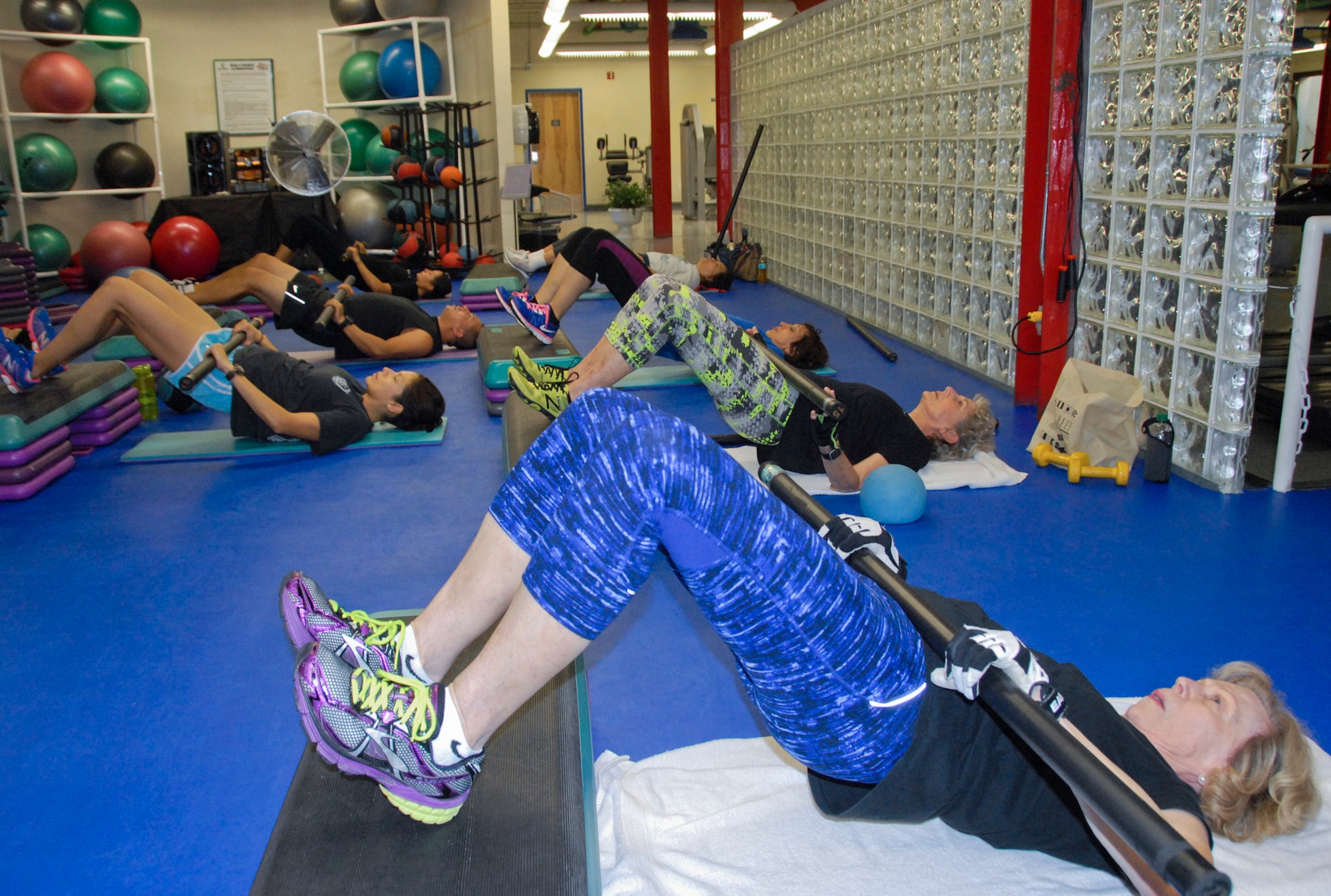 Tech. Sgt. Adrienne Tarin-Yatco (far left), of the 96th Aerospace Medicine Squadron, and members of the Muscle Max strength training class, perform a bridge with weight at the Fitness Annex at Eglin Air Force Base, Fla.  The class is available to help anyone with base access maintain their fitness through the holiday season and year-round.  (U.S. Air Force photo/Kevin Gaddie)