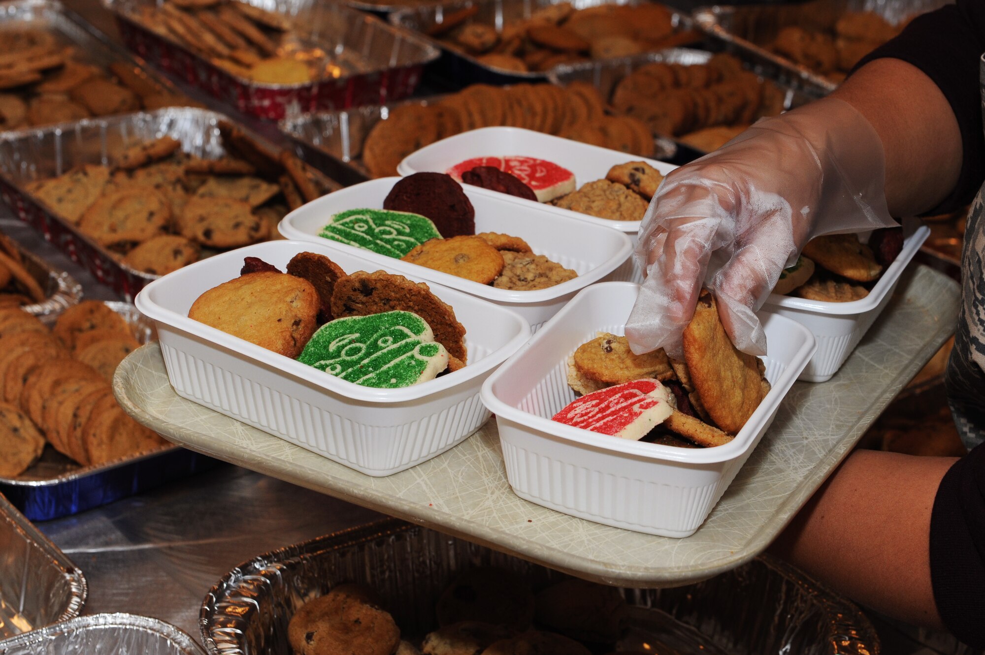 A volunteer places a cookie into a container during the holiday cookie drive on Kadena Air Base, Japan, Dec. 9, 2014. More than 50 volunteers from several agencies on base helped pack the cookies into individual portions and deliver them to approximately 2,100 Airmen, soldiers, sailors and Marines living in dormitories on Kadena. (U.S. Air Force photo by Airman 1st Class Zade C. Vadnais/Released)