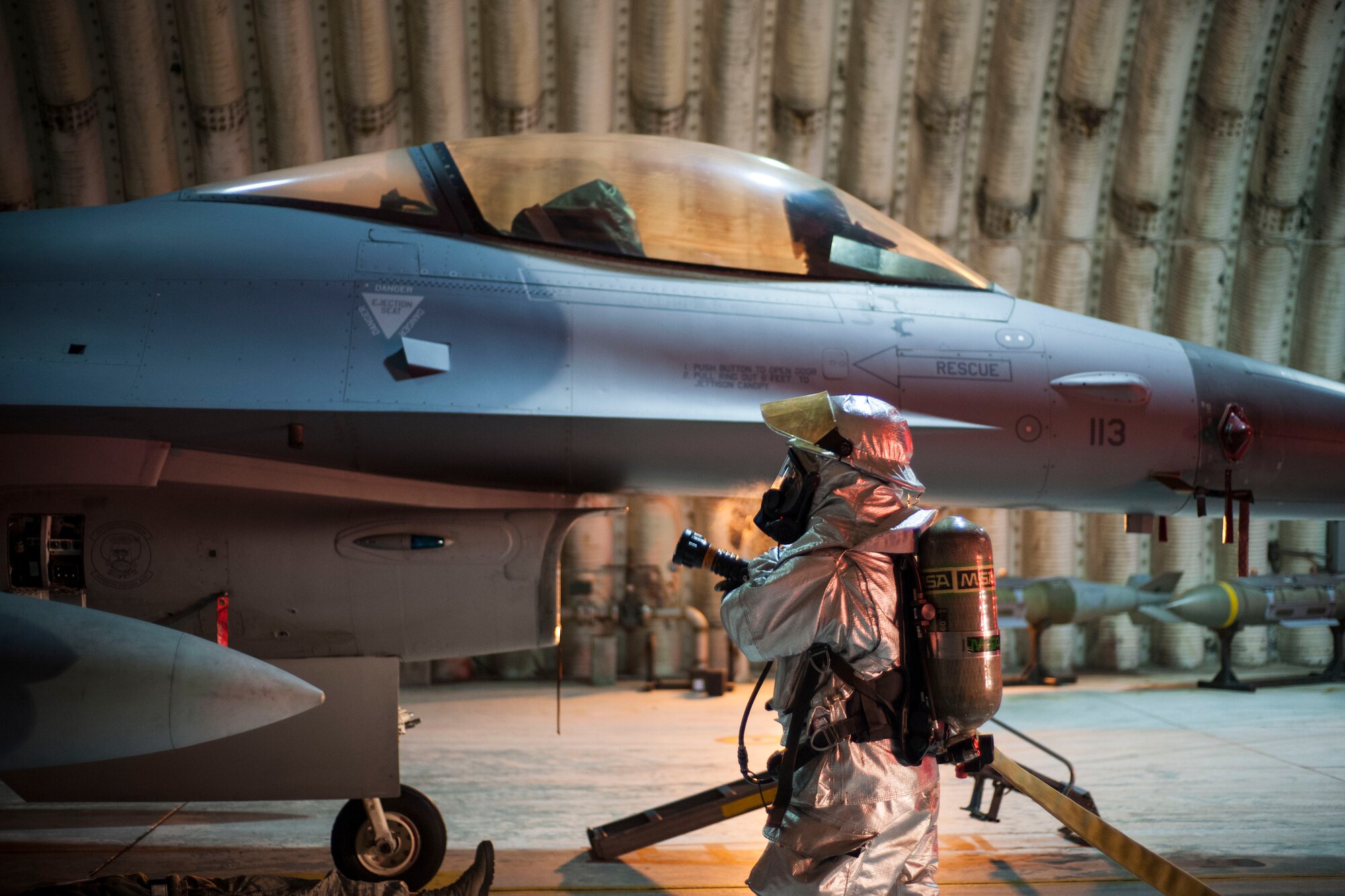 An 8th Civil Engineer Squadron fire department member simulates hosing down an F-16 Fighting Falcon following a mass evacuation during Exercise Beverly Bulldog 15-1 at Kunsan Air Base, Republic of Korea, Dec. 9, 2014. The eight-day exercise took place in an austere environment that tested the Wolf Pack’s ability to respond to wartime and armistice conditions. (U.S. Air Force photo by Senior Airman Katrina Heikkinen/Released)