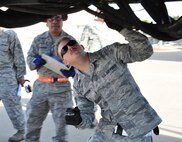 Staff Sgt. Andrew Anderson, 73rd Aerial Port Squadron ramp agent, inspects the undercarriage of a Tunner 60k aircraft cargo loader/transporter at Naval Air Station Fort Worth Joint Reserve Base, Texas, Dec. 6, 2014. The machine, delivered on a 433rd Airlift Wing C-5, provided an historic opportunity for nearly 30 aerial port Airmen to receive crucial combat training requirements prior to a deployment. (U.S. Air Force photo by Master Sgt. Julie Briden-Garcia) 