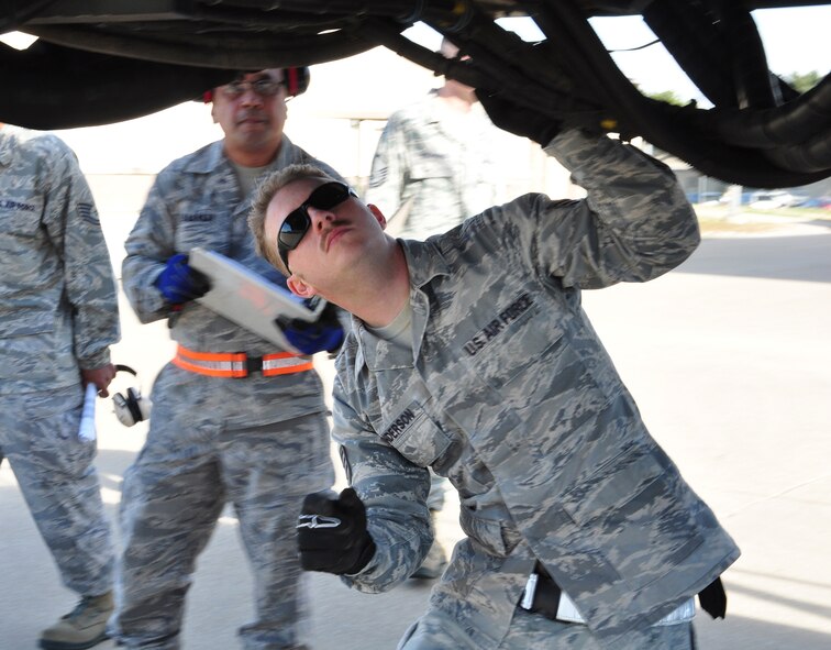 Staff Sgt. Andrew Anderson, 73rd Aerial Port Squadron ramp agent, inspects the undercarriage of a Tunner 60k aircraft cargo loader/transporter at Naval Air Station Fort Worth Joint Reserve Base, Texas, Dec. 6, 2014. The machine, delivered on a 433rd Airlift Wing C-5, provided an historic opportunity for nearly 30 aerial port Airmen to receive crucial combat training requirements prior to a deployment. (U.S. Air Force photo by Master Sgt. Julie Briden-Garcia) 