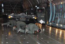 The 73rd Aerial Port Squadron Airmen prepare to drive a Tunner 60k aircraft cargo loader/transporter off the ramp for a historical training opportunity while the 433rd Airlift Wing C-5 aircrew ensures all systems are ready before offloading at Naval Air Station Fort Worth Joint Reserve Base, Texas, Dec. 6, 2014.  Borrowed from Joint Base San Antonio's 502nd Logistics Readiness Squadron, the 60k loader gave nearly 30 of the 73 APS Airmen combat operational training requirements that are crucial prior to a deployment. (U.S. Air Force photo by Master Sgt. Julie Briden-Garcia)