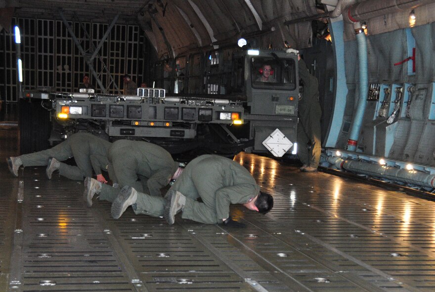 The 73rd Aerial Port Squadron Airmen prepare to drive a Tunner 60k aircraft cargo loader/transporter off the ramp for a historical training opportunity while the 433rd Airlift Wing C-5 aircrew ensures all systems are ready before offloading at Naval Air Station Fort Worth Joint Reserve Base, Texas, Dec. 6, 2014.  Borrowed from Joint Base San Antonio's 502nd Logistics Readiness Squadron, the 60k loader gave nearly 30 of the 73 APS Airmen combat operational training requirements that are crucial prior to a deployment. (U.S. Air Force photo by Master Sgt. Julie Briden-Garcia)