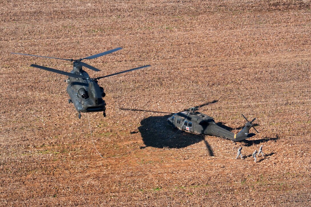 Soldiers walk away from a downed UH-60 Black Hawk helicopter before an Army CH-47 Chinook helicopter lifts it up for slingload movement back to McEntire Joint National Guard Base in Eastover, S.C., Dec. 7, 2014.