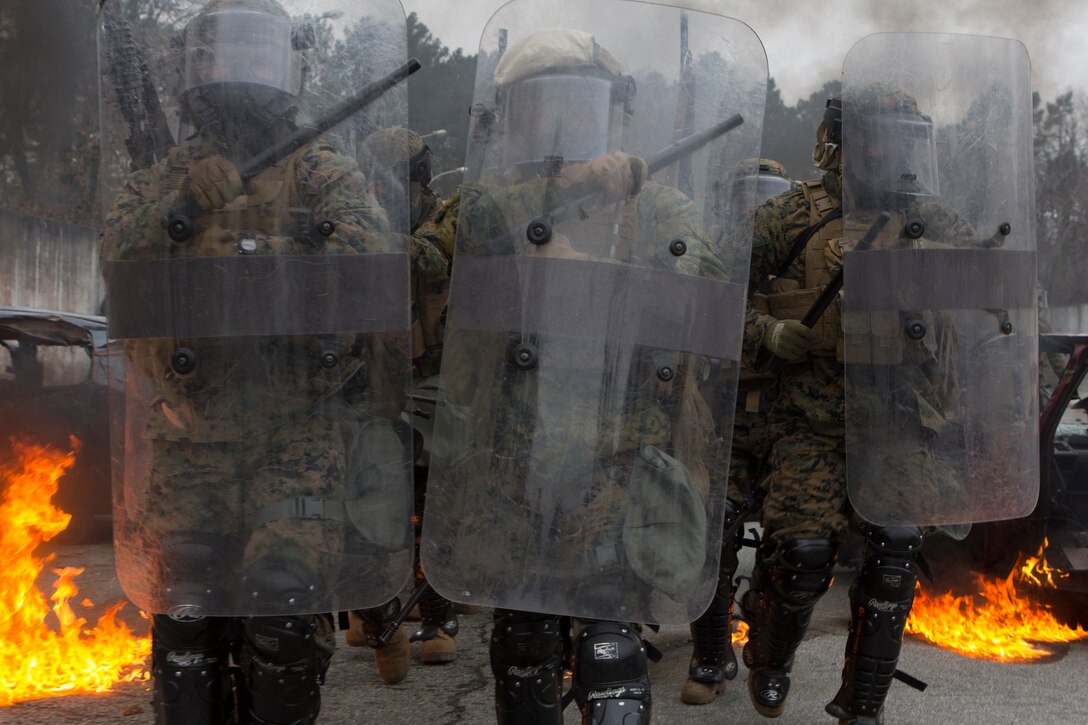 U.S. Marines with SPMAGTF Crisis Response – Africa march through flames from Molotov cocktails towards role-playing rioters while training in crowd and riot control techniques at the National Gendarmerie Training Center in St. Astier, France, Dec. 2, 2014. The exercise, which was conducted with the French Gendarmerie, allowed the Marines to gain greater knowledge of non-lethal tactics, techniques and procedures while enhancing interoperability with the French Gendarmerie and strengthening the U.S. partnership with France.  (U.S. Marine Corps photo by Cpl. Jeraco Jenkins/Released).