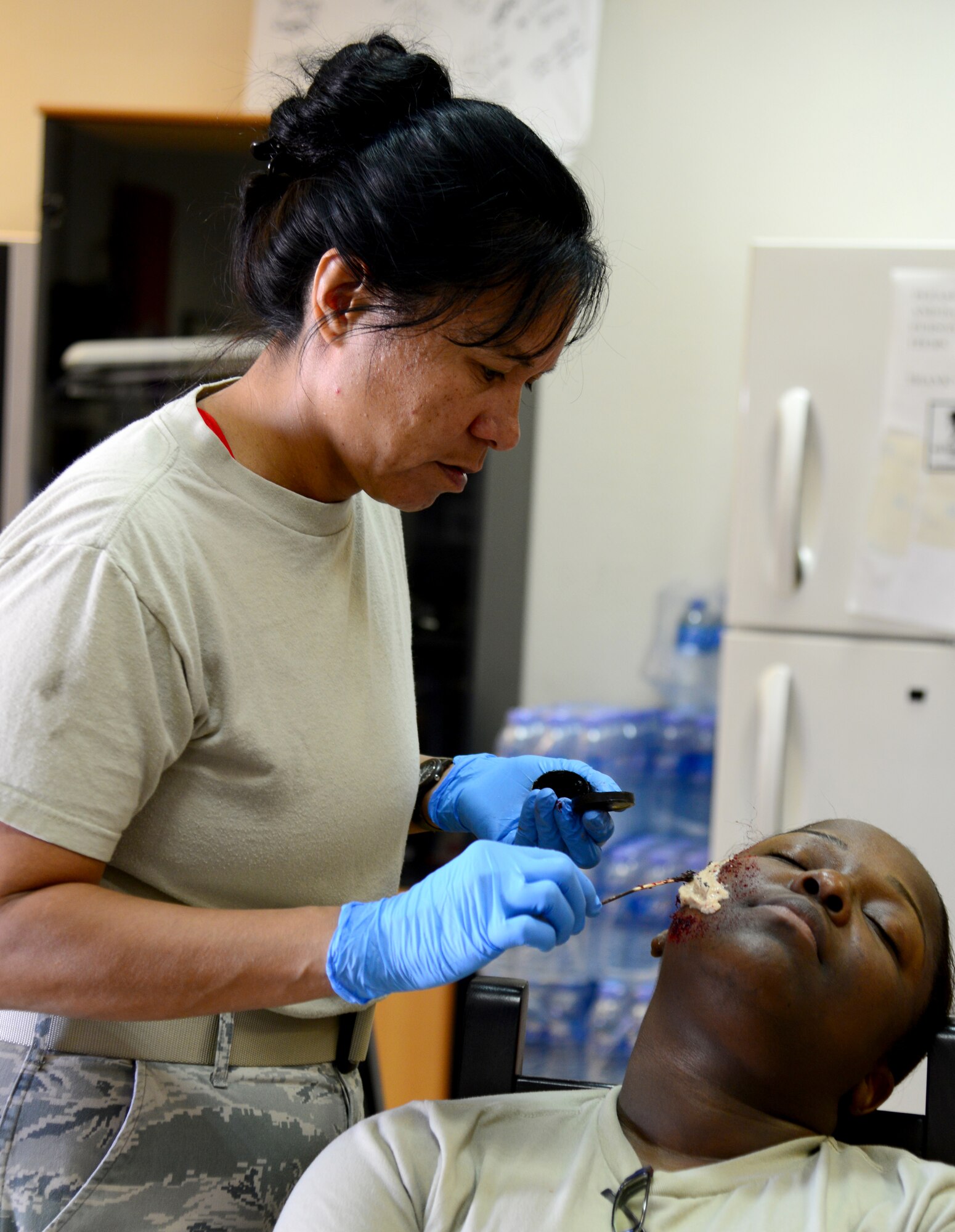 U.S. Air Force Maj. Michelle Dimoff, 379th Expeditionary Medical Operations Squadron, applies moulage to a simulated victim of an active shooter exercise, Dec. 10, 2014, at Al Udeid Air Base, Qatar. Dimoff is deployed from Nellis Air Force Base, Nev. The fake injuries create a sense of realism for first responders and enhance the effectiveness of the training conducted. (U.S. Air Force photo by Senior Airman Kia Atkins)