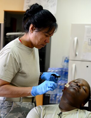U.S. Air Force Maj. Michelle Dimoff, 379th Expeditionary Medical Operations Squadron, applies moulage to a simulated victim of an active shooter exercise, Dec. 10, 2014, at Al Udeid Air Base, Qatar. Dimoff is deployed from Nellis Air Force Base, Nev. The fake injuries create a sense of realism for first responders and enhance the effectiveness of the training conducted. (U.S. Air Force photo by Senior Airman Kia Atkins)