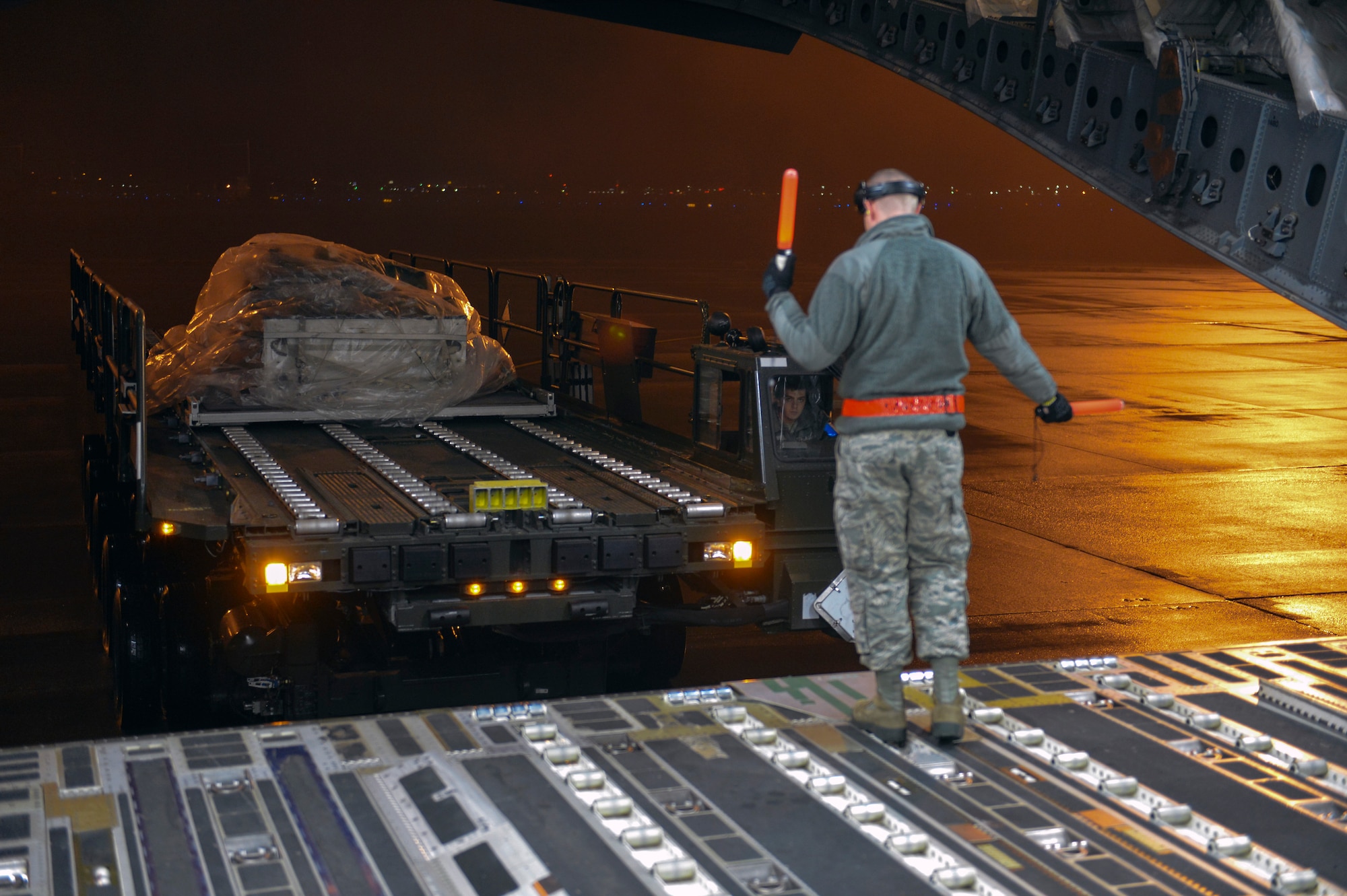 Airman 1st Class Jace Fore spots a vehicle loader toward a C-17 Globemaster III aircraft Dec. 6, 2014, at Joint Base Lewis-McChord, Wash. in support of a joint forcible entry exercise. Aerial porters loaded cargo, meals and offered fleet support to the five jets simultaneously without a single safety discrepancy or delay. Fore is a ramp services technician  with the 62nd Aerial Port Squadron. (U.S. Air Force photo/Staff Sgt. Russ Jackson)