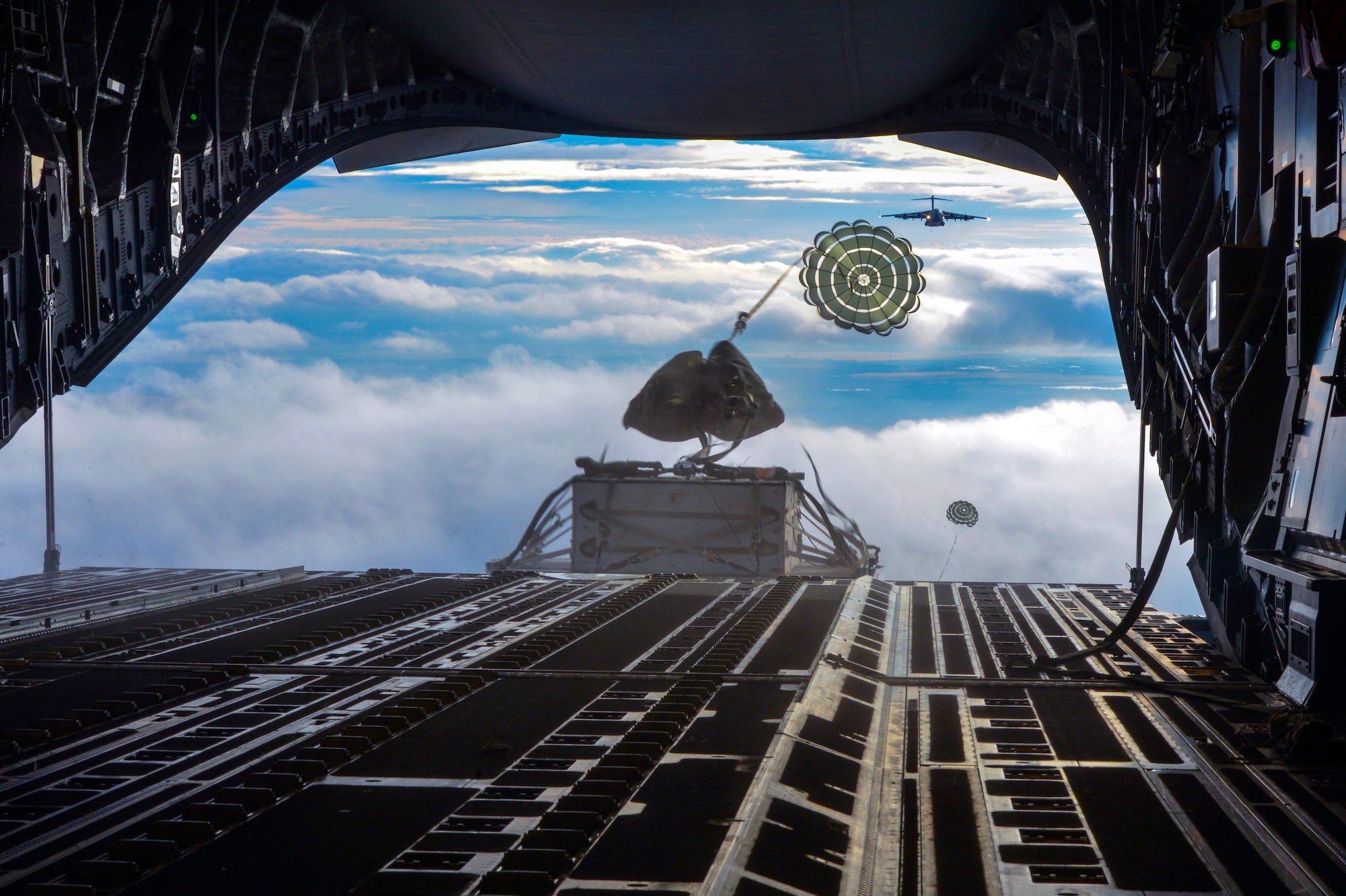 Two heavy container delivery systems plunge from the back of a C-17 Globemaster III aircraft to forces on the ground during the simulated Rainier War Dec. 6, 2014, over the Rainier drop zone, Wash. The Joint Concept for Entry Operations doctrine defines forcible entry as the seizing and holding of a lodgment in the face of armed opposition. (U.S. Air Force photo/Staff Sgt. Russ Jackson)