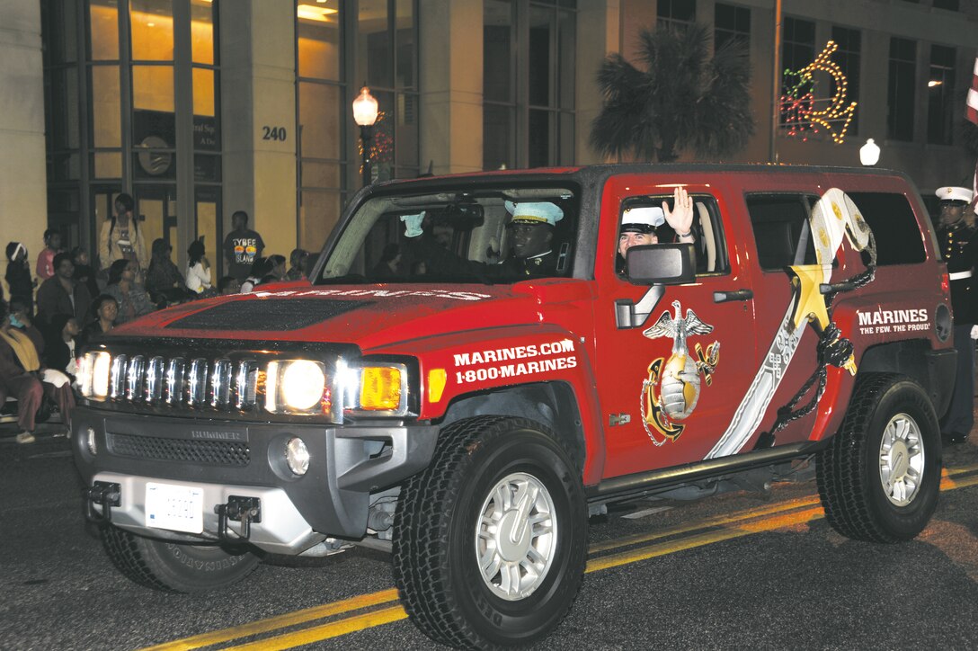 Sgt. John Alday, Marine Corps Recruiting Command, waves to the crowd during the 24th annual Celebration of Lights parade in downtown Albany, Dec. 6.  Alday served as the driver for Lt. Col. Nathaniel Robinson, executive officer, and Sgt. Maj. Kenneth Agee, sergeant major, Marine Corps Logistics Base Albany.