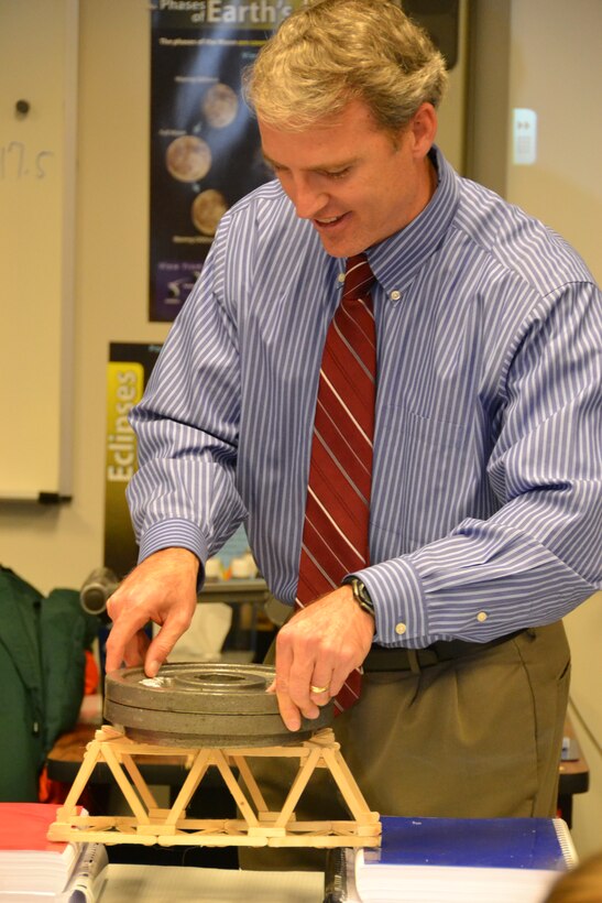 WINCHESTER, Va. - Engineer Bob Thomas adds weights to the bridge that students built to demonstrate load.