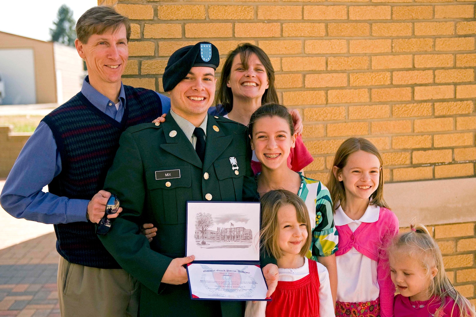 Private 1st Class Scott Wayne proudly holds his newly earned high school diploma while posing for photos with his family members at the Patriot Academy's first graduation ceremony at the Muscatatuck Urban Training Center in Butlerville, Ind., March 18, 2010. The Army National Guard's Patriot Academy is the U.S. military's first accredited high school.