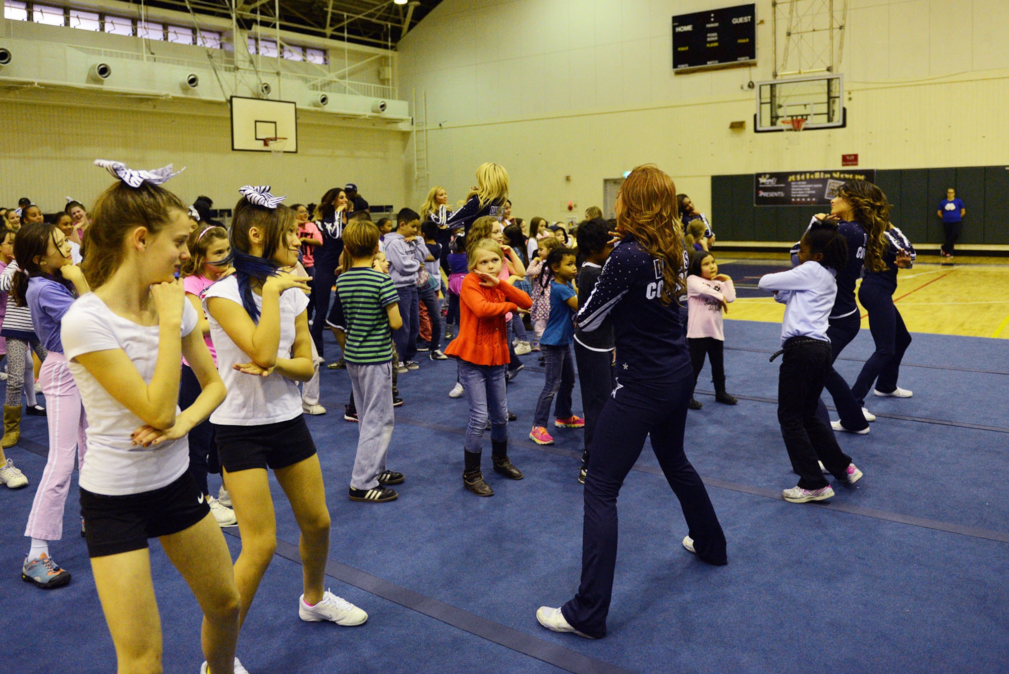 Youth from Yokota Air Base, Japan, join Dallas Cowboys Cheerleaders in a fitness routine at the Samurai Fitness Center Dec. 9, 2014. While at Yokota, the cheerleaders talked with the youth about exercising. (U.S. Air Force photo by Senior Airman Desiree Economides/Released)