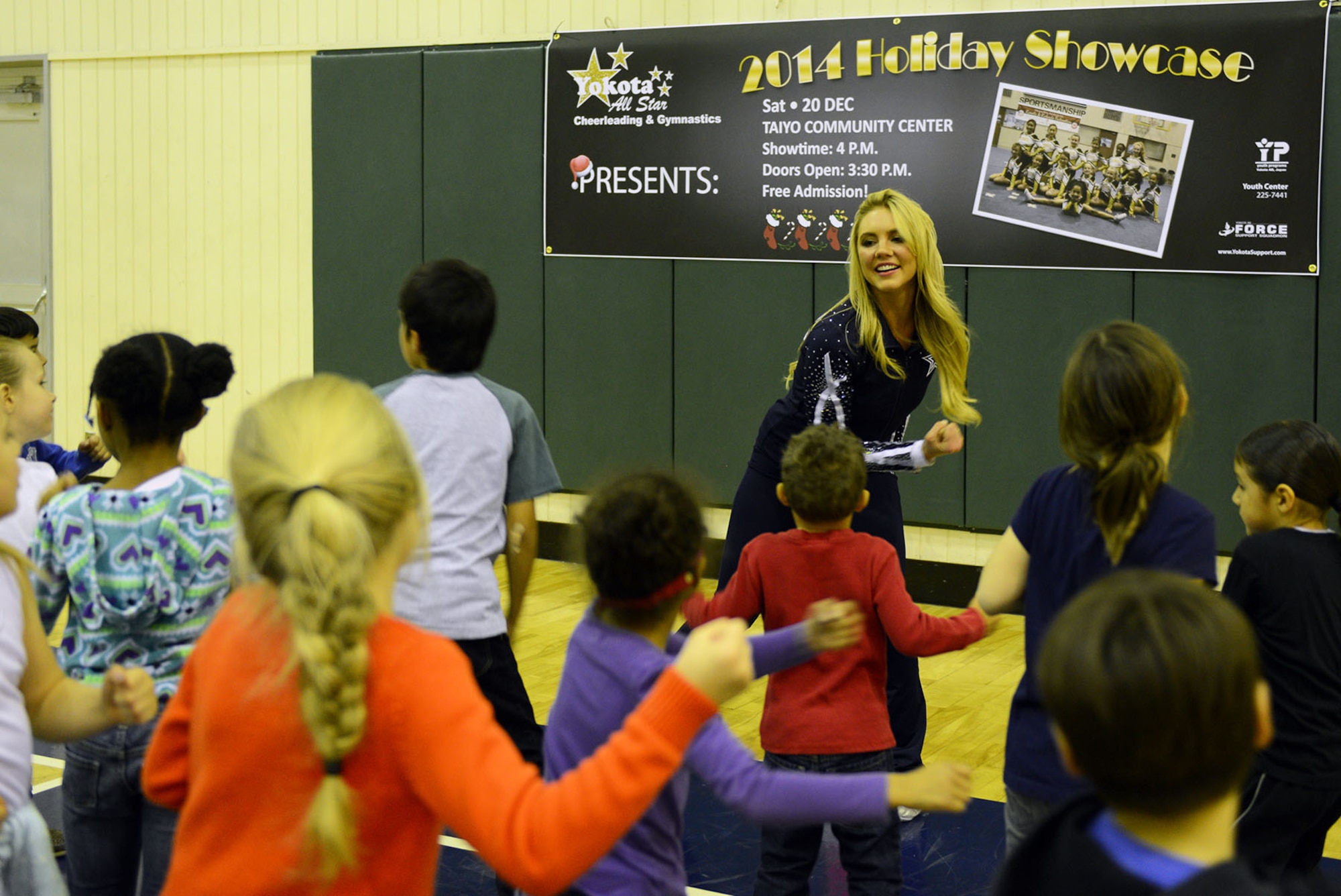 A Dallas Cowboys Cheerleader leads youth in a fitness routine at the Samurai Fitness Center Dec. 9, 2014, at Yokota Air Base, Japan.  As part of their USO tour, the cheerleaders held a health and fitness clinic for youth at Yokota. (U.S. Air Force photo by Senior Airman Desiree Economides/Released)