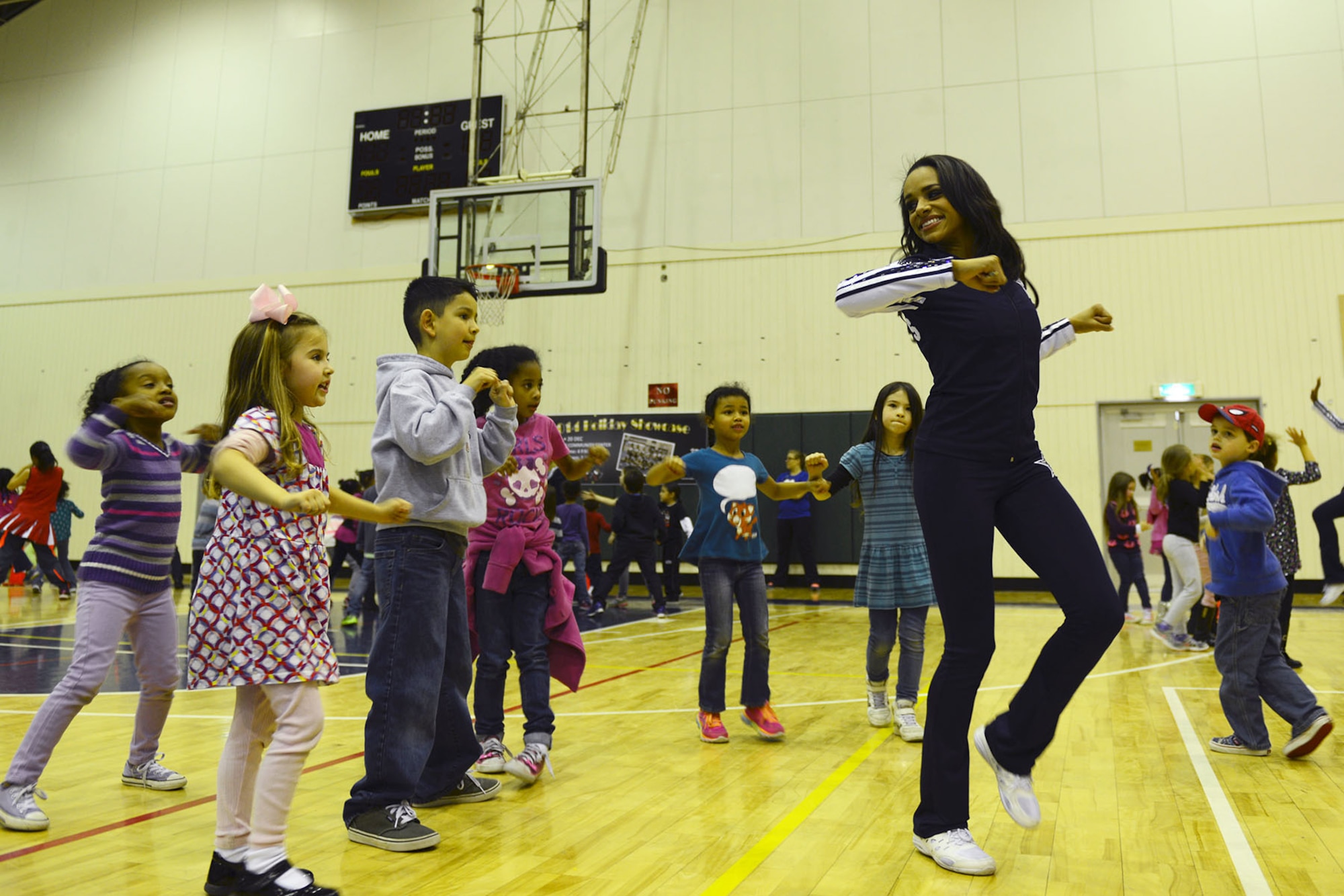 A Dallas Cowboys Cheerleader teaches youth an aerobic move Dec. 9, 2014, at Yokota Air Base, Japan. As part of their USO tour, the cheerleaders held a health and fitness clinic at the Samurai Fitness Center. (U.S. Air Force photo by Senior Airman Desiree Economides/Released)