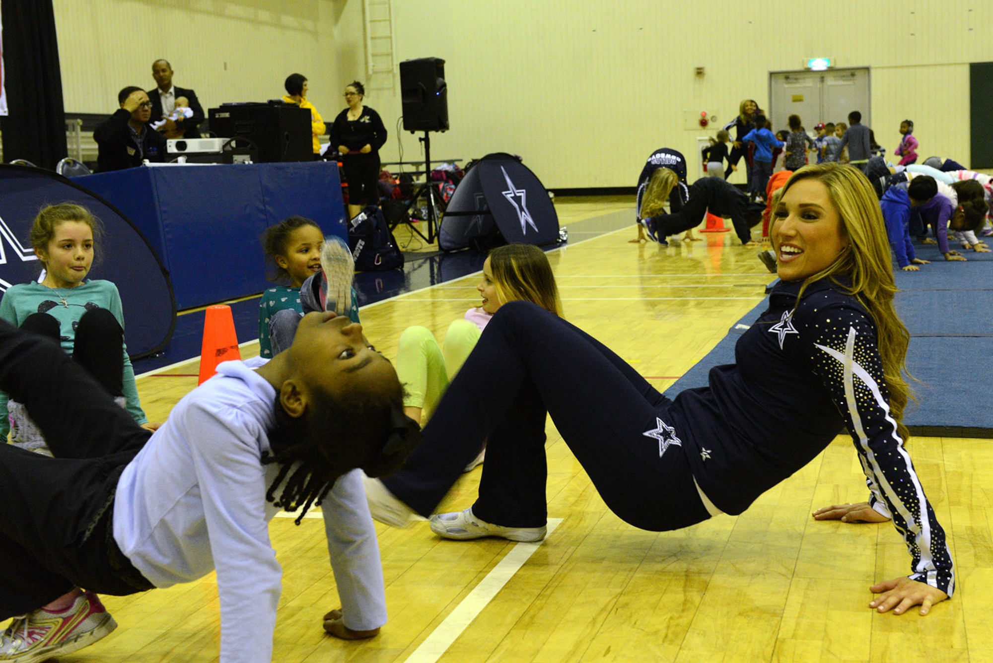 A Dallas Cowboys Cheerleader does an exercise with  youth at the Samurai Fitness Center Dec. 9, 2014, at Yokota Air Base, Japan. During their USO tour, the cheerleaders broke off in small groups and did different fitness exercises. (U.S. Air Force photo by Senior Airman Desiree Economides/Released)  