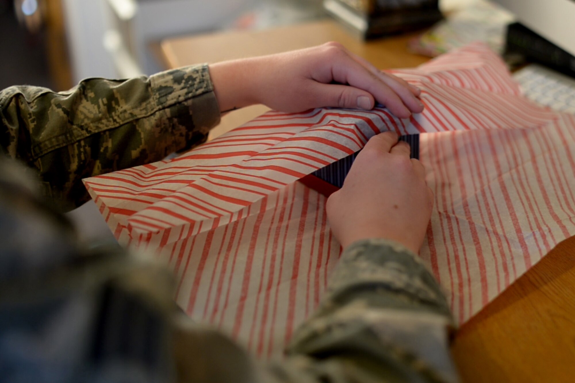 Senior Airman Lucille Perkins-Wagel, 28th Force Support Squadron services technician, wraps a present to send to her family in her dorm room at Ellsworth Air Force Base, S.D., Dec. 4, 2014. Many agencies provide Airmen with activities to participate in during the holiday season to include the bowling alley, the Raider Café and the base chapels.  (U.S. Air Force Photo by Senior Airman Jordan Thompson/Released)