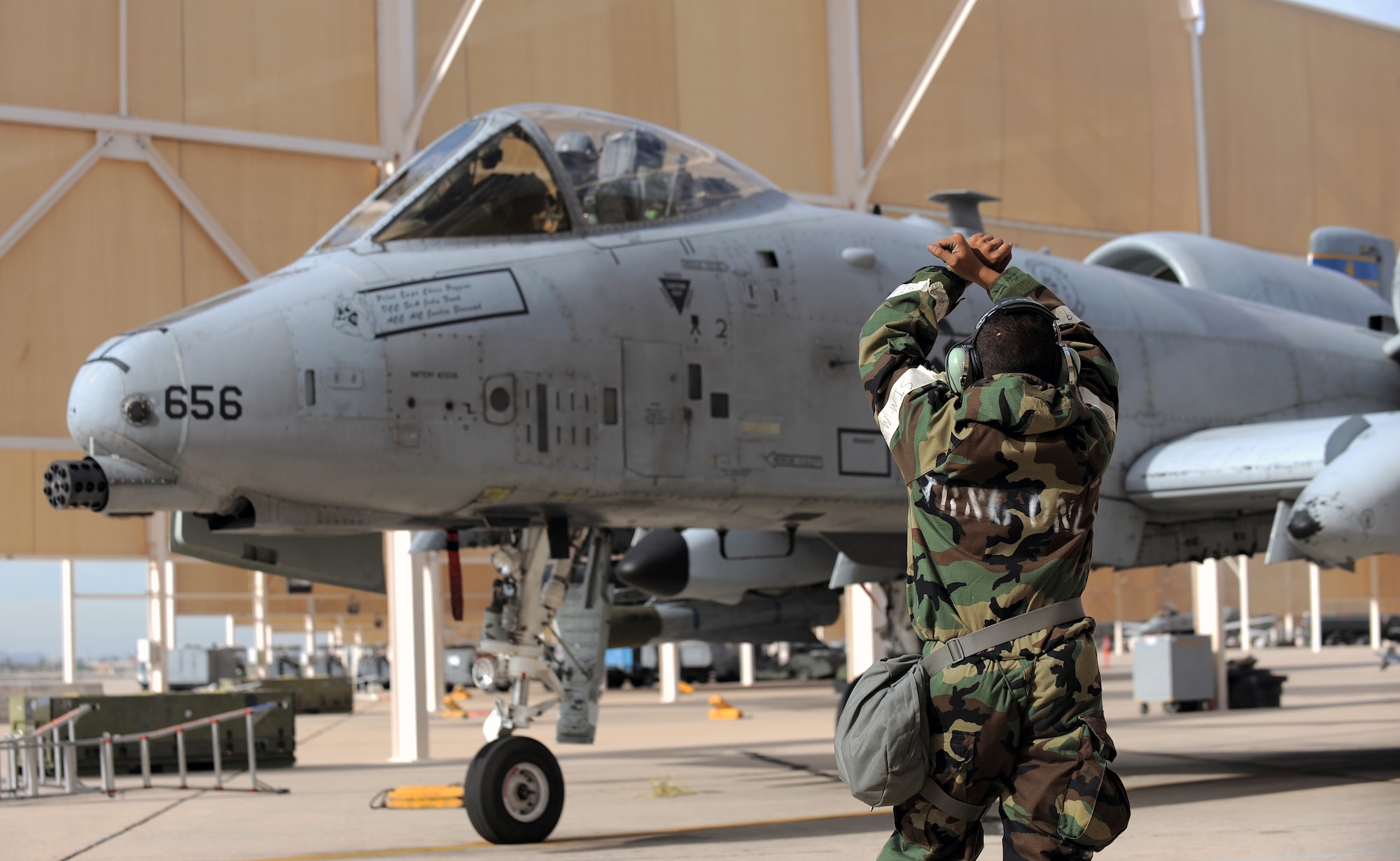U.S. Air Force Senior Airman Fernando Sorto, 355th Aircraft Maintenance Squadron crew chief, clears an A-10 Thunderbolt II to launch during an operational readiness exercise at Davis-Monthan Air Force Base, Ariz., Dec. 9, 2014. The 355th Fighter Wing practiced their ability to survive and operate under simulated conventional chemical and biological conditions. (U.S. Air Force photo by Airman 1st Class Chris Drzazgowski/Released) 
