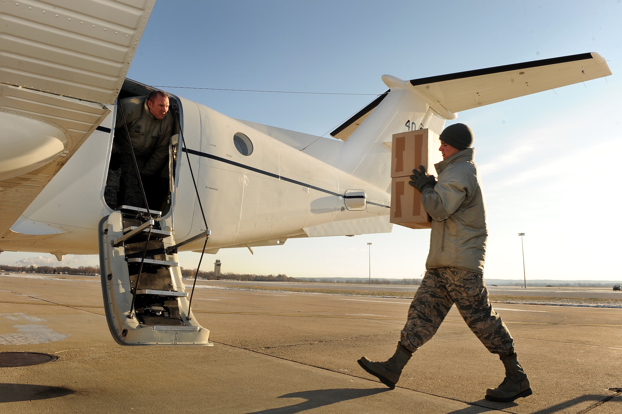 U.S. Air Force Staff Sgt. Jonathan Clay, a Defense Courier Station Offutt courier, hands classified packages to fellow courier, U.S. Air Force Tech Sgt. John King, on the flightline at Offutt Air Force Base, Neb., Nov. 18, 2014. The Defense Courier Station Offutt is tasked with servicing nine states and 130 customers, comprising the second largest geographical area of responsibility for all of the 18 worldwide defense courier units. (U.S. Air Force photo by Josh Plueger/Released)