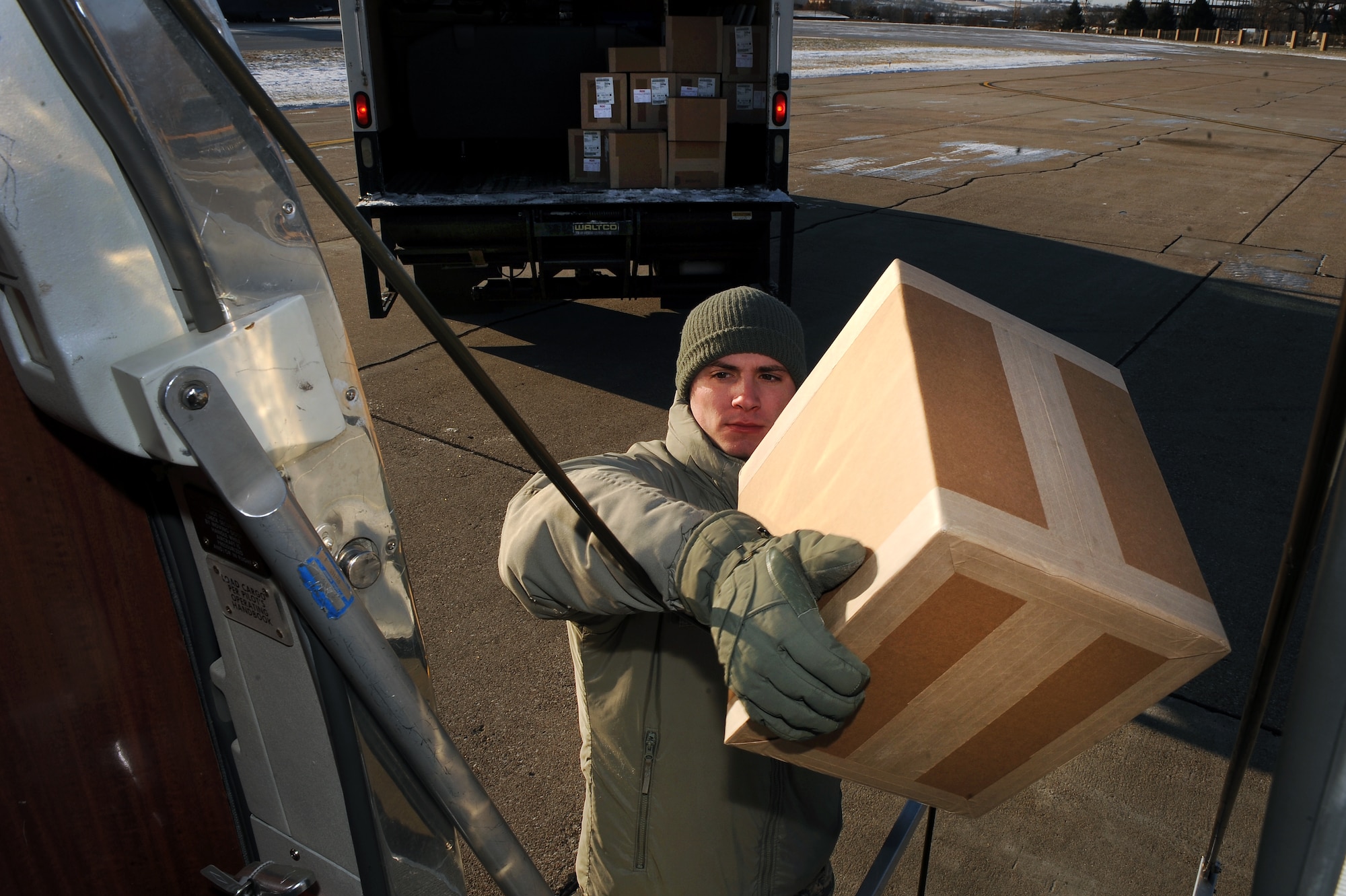 U.S. Air Force Staff Sgt. Jonathan Clay, a Defense Courier Station Offutt courier, transfers packages from a box truck to the fuselage of a C-12 aircraft at Offutt Air Force Base, Neb., Nov. 18, 2014. Clay along with another courier will hand deliver the packages at numerous points across the Midwest all within one duty day.  (U.S. Air Force photo by Josh Plueger/Released)