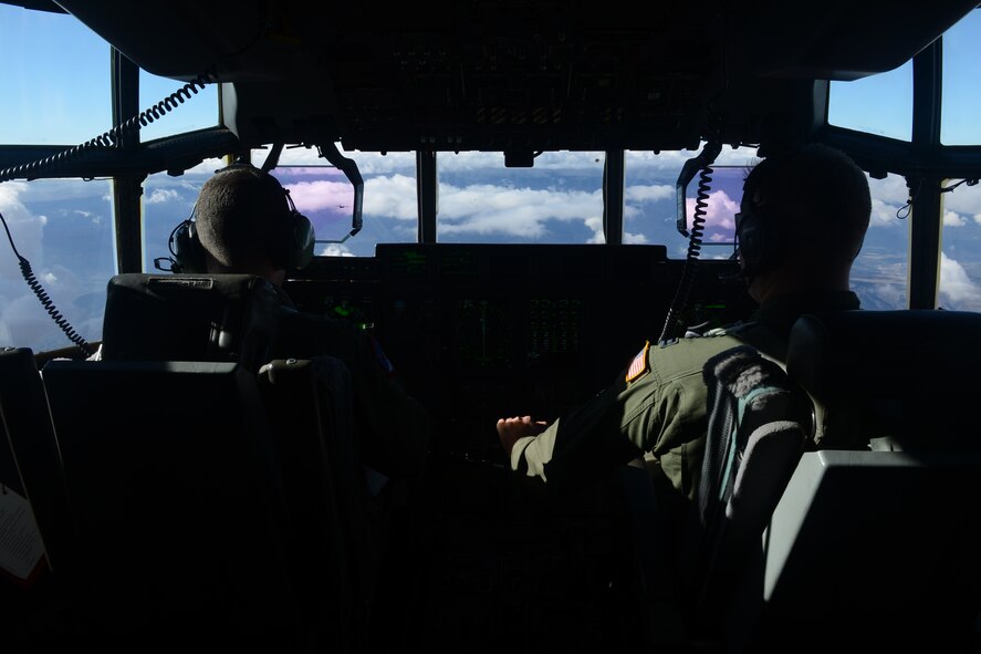 U.S. Air Force Capt. Shawn Tupta, 317th Operation Support Squadron, left, and Capt. Matt Crowley, 39th Airlift Squadron, both C-130J Super Hercules pilots, fly to a joint forcible entry exercise Dec. 6, 2014, at Nellis Air Force Base, Nev. During the exercise, eleven 317th Airlift Group C-130Js flew in a formation while dropping U.S. Army personnel to simulate an airfield seizure. (U.S. Air Force photo by Airman 1st Class Autumn Velez/Released)