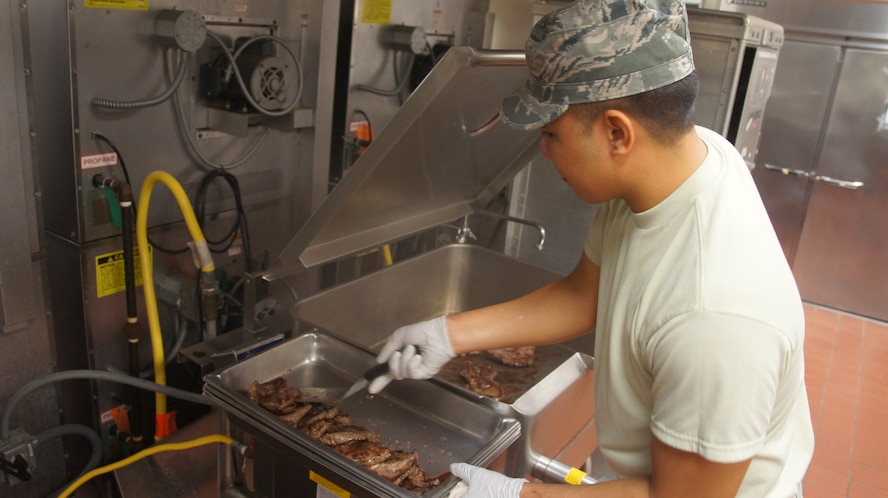 Airman 1st Class Alexander Kanahele-Mone, a services apprentice with the 154th Force Support Squadron, prepares rib-eye steaks for the Hawaii Air National Guard's traditional holiday meal service Dec. 6, 2014, at Joint Base Pearl Harbor-Hickam. The annual holiday meal provided Hawaii National Guard commanders and senior enlisted leaders an opportunity to show their gratitude for the service their airmen have provided throughout the year. (Hawaii Air National Guard photo by Tech. Sgt. Andrew Jackson/Released)

