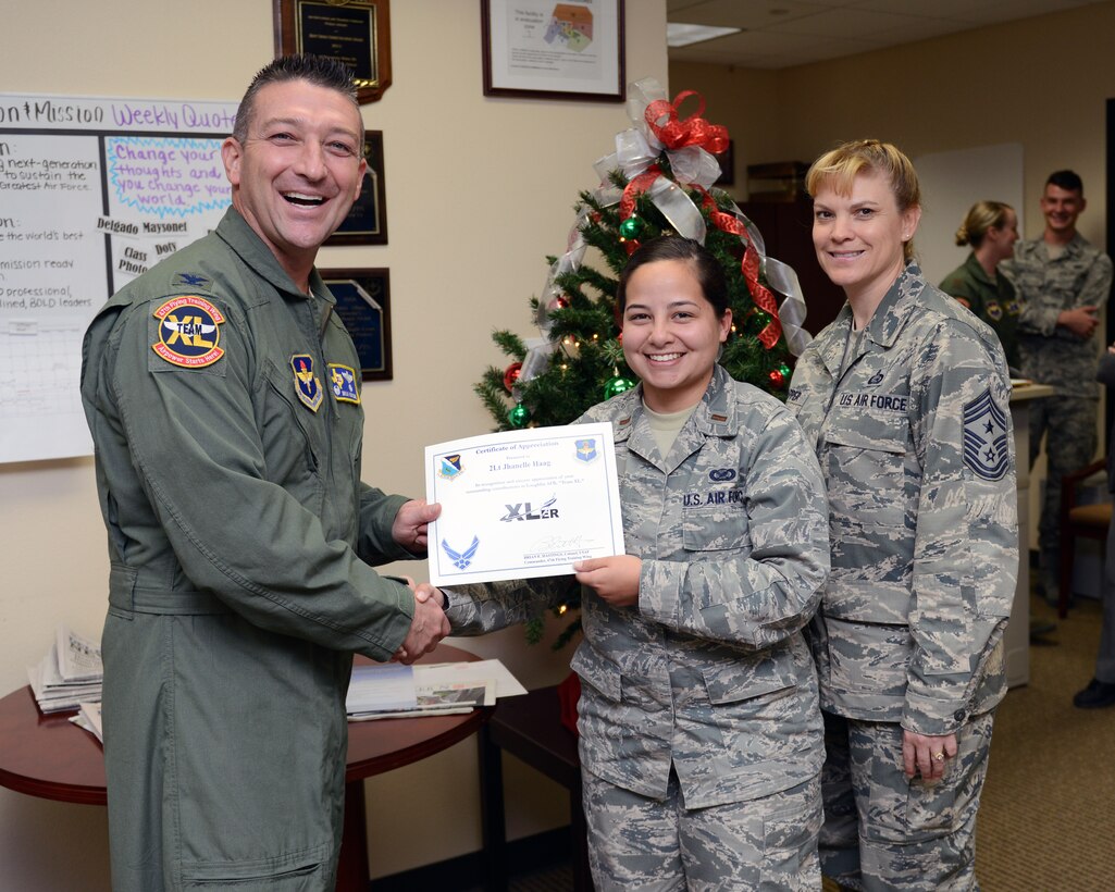 Second Lt. Jhanelle Haag, center, 47th Flying Training Wing Public Affairs officer, poses with Col. Brian Hastings, left, 47th FTW commander, and Chief Master Sgt. Teresa Clapper, right, 47th FTW command chief, after being presented the XLer of the week award here Dec. 10, 2014. The XLer is a weekly award chosen by wing leadership and is presented to those who consistently make outstanding contributions to their unit and Laughlin. (U.S. Air Force photo by Airman 1st Class Jimmie D. Pike)(Released)