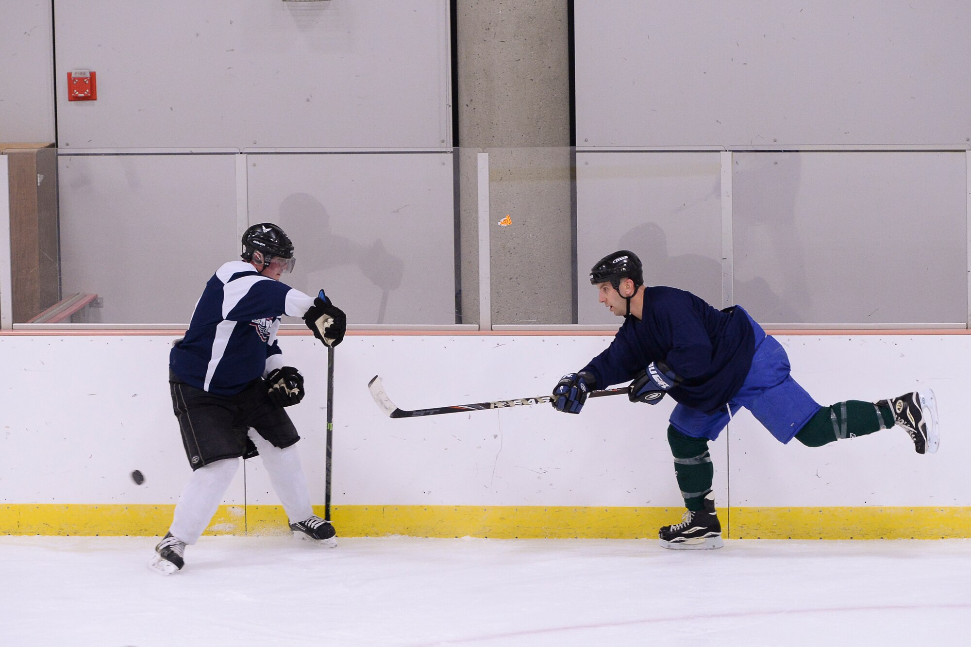 Retired U.S. Air Force Master Sgt. Chris Malenius and Lt. Col. David Michaud, the 353rd Combat Training Squadron commander, both Eielson Air Force Base hockey team defensemen, scrimmage head-to-head Nov. 18, 2014, during practice at Fort Wainwright, Alaska. Eielson's hockey team was preparing for the upcoming 2014 Commander's Cup game at the Carlson Center against players from Fort Wainwright. (U.S. Air Force photo by Senior Airman Peter Reft/Released)