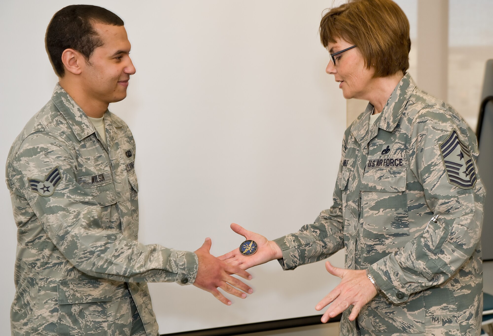 Senior Airman Stanley Wilson, 436th Comptroller Squadron, receives a coin from Chief Master Sgt. Victoria Gamble, Air Mobility Command chief Dec. 4, 2014, at the Health Promotions Flight on Dover Air Force Base, Del. Wilson was recognized by the chief for his government travel card expertise and commitment to excellence. (U.S. Air Force photo/Roland Balik)