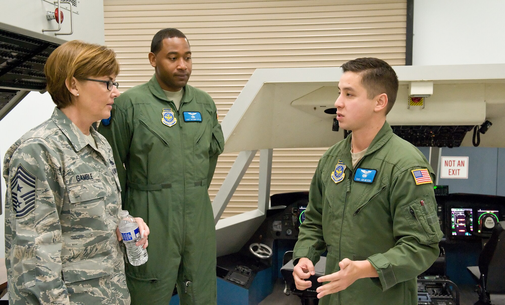 Staff Sgt. Jon Meyers, 9th Airlift Squadron instructor flight engineer, right, and Tech. Sgt. Antonio Little, 9th Airlift Squadron instructor loadmaster, center, talk with Chief Master Sgt. Victoria Gamble, Air Mobility Command chief, left, Dec. 4, 2014, at Dover Air Force Base, Del. Meyers and Little briefed Gamble on the advantages and cost-saving benefits of using the C-5 aircraft maintenance system trainer for flight engineers and loadmasters. (U.S. Air Force photo/Roland Balik)
