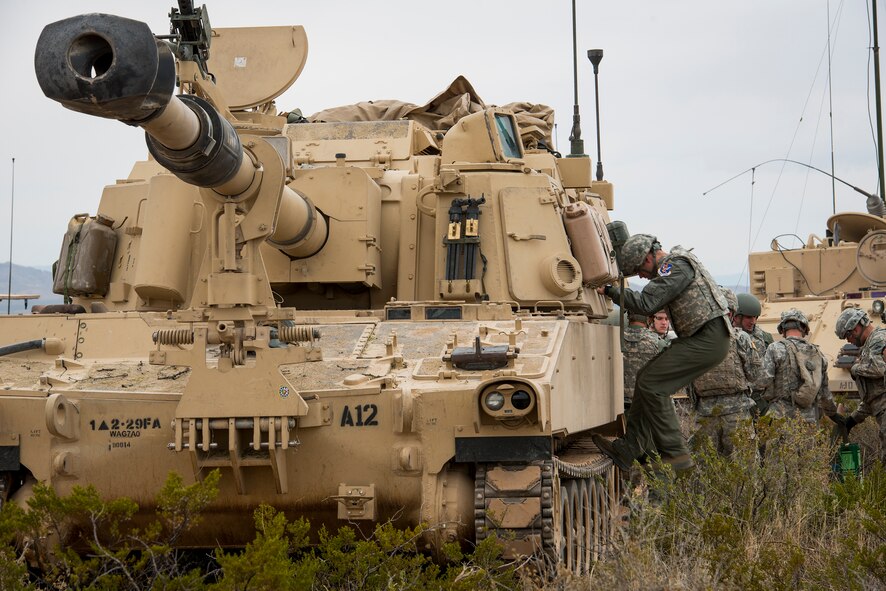 Airmen from the 74th Fighter Squadron and the 23d Maintenance Group speak with soldiers from Alpha Battery, 2nd Battalion, 29 Field Artillery, 1st Armored Division, about the mission and capabilities of the M109A6 Paladin howitzer during Exercise IRON STRIKE, Dec. 4, 2014, at the Oro Grande Range Complex, Fort Bliss, Texas. IRON STRIKE integrates armored units, artillery units and A-10 aircraft for realistic joint fire and close air support execution. (U.S. Air Force Photo by Airman 1st Class Ryan Callaghan/Released)