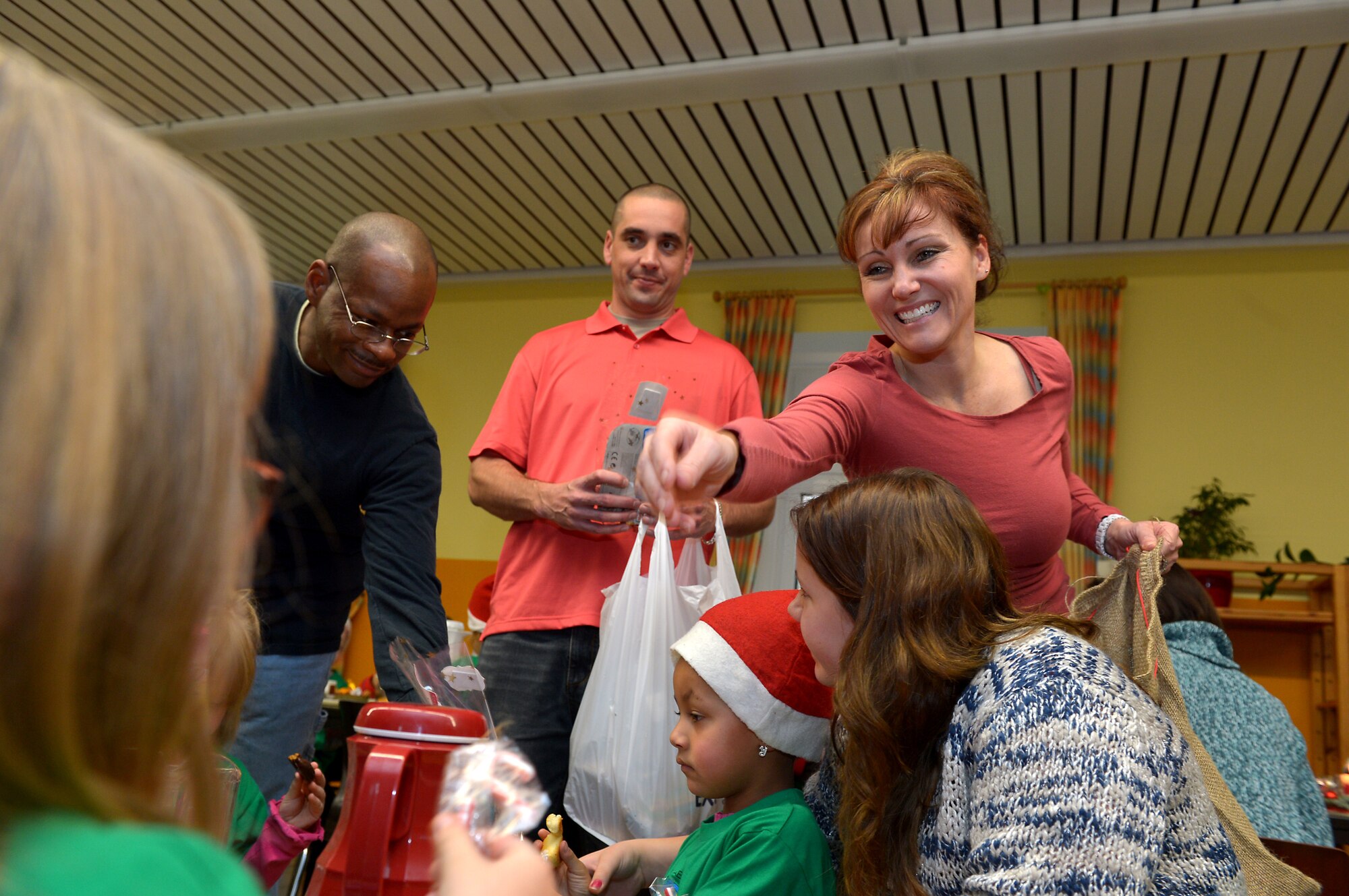 Deborah Gates, spouse of U.S. Air Force Chief Master Sgt. Brian Gates, 52nd Fighter Wing command chief; and U.S. Air Force Chief Master Sgt. Shawn Lee and U.S. Air Force Master Sgt. David Dulaney, both from the 52nd Civil Engineer Squadron, pass out gifts at St. Martin School in Bitburg, Germany, Dec. 8, 2014. Spangdahlem civil engineers led two major events each year for these special needs children: “St. Martin’s Day” Special Olympics at Spangdahlem and this visit to pass out gifts. (U.S. Air Force photo by Airman 1st Class Kyle Gese/Released)